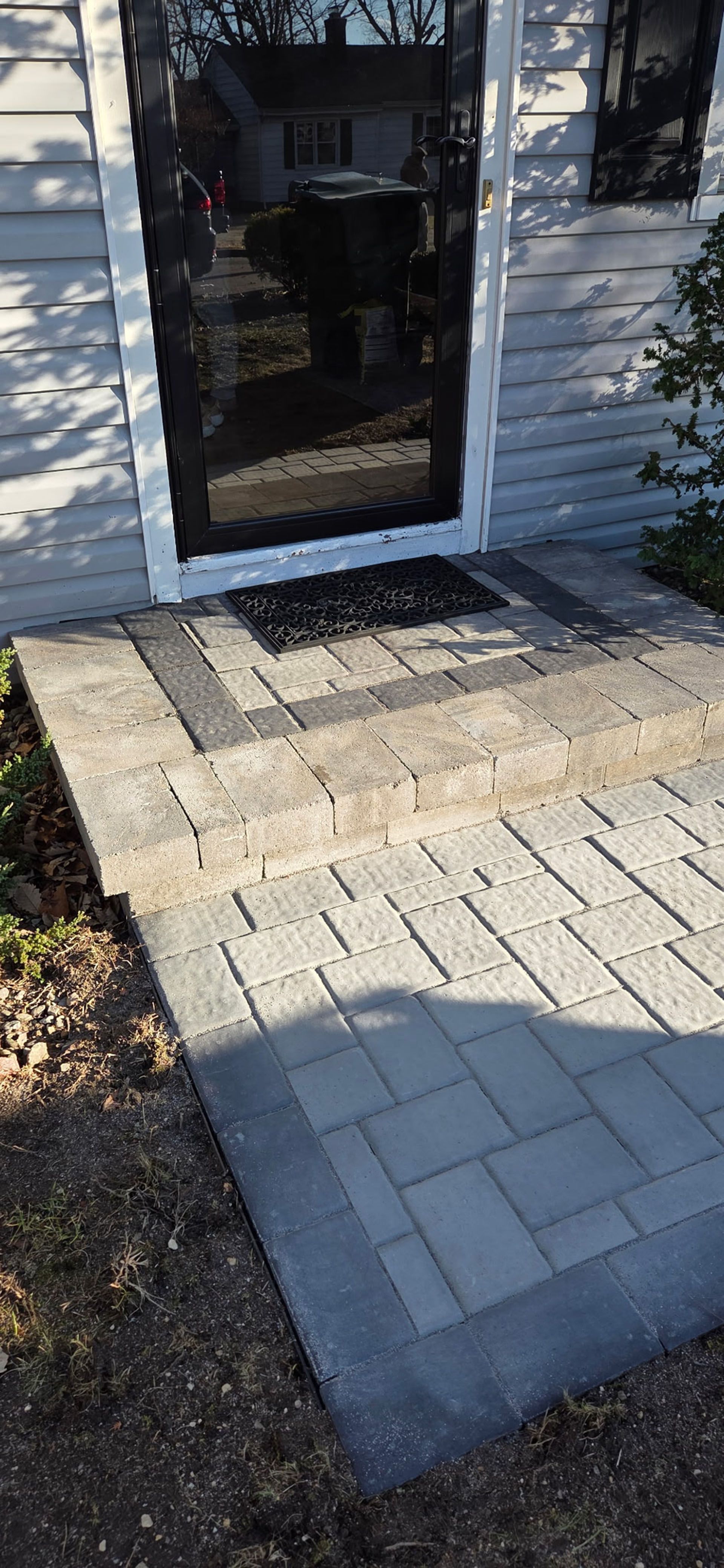 Brick pathway leading to a door with a screen.