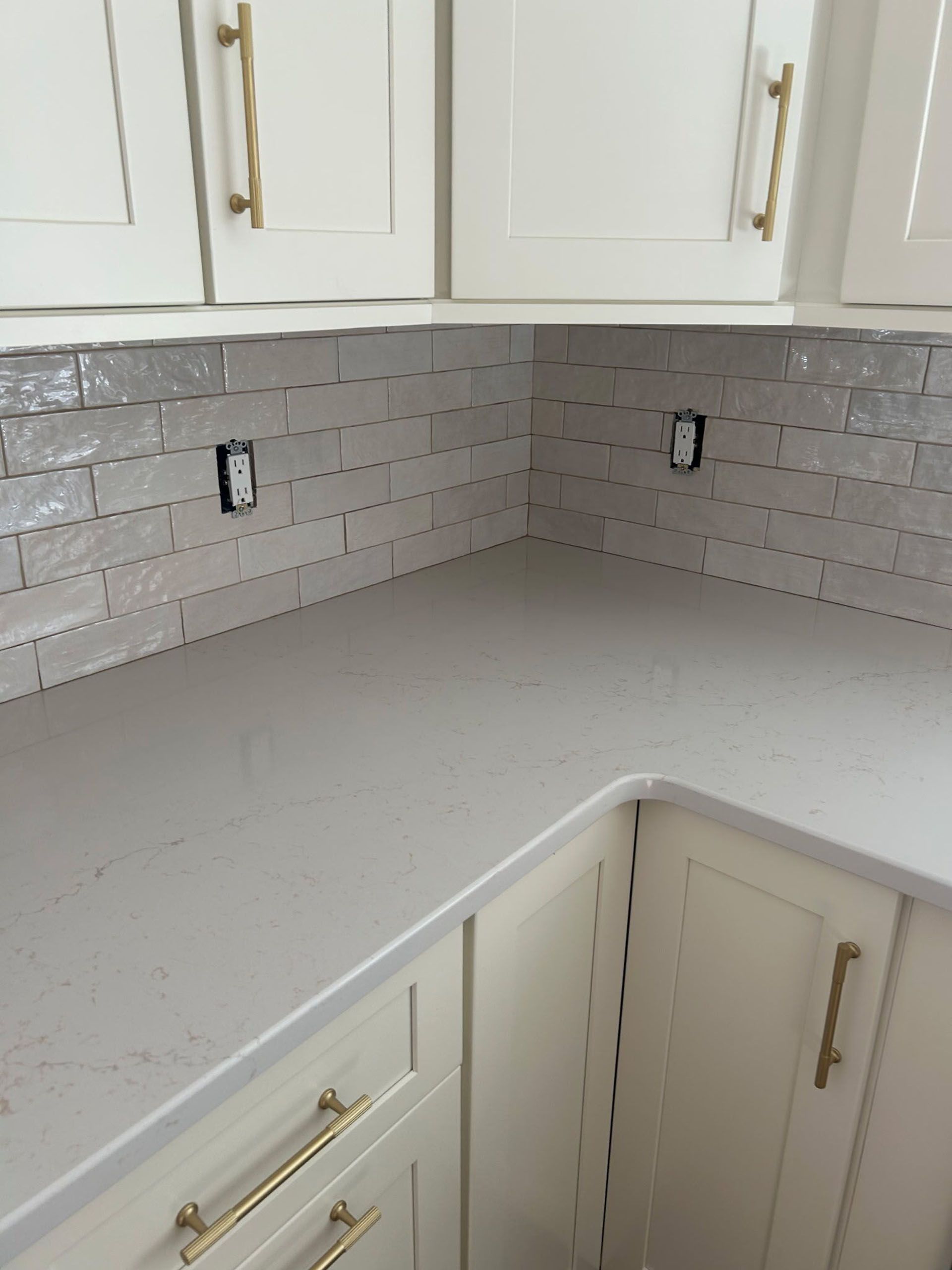 Kitchen corner with white cabinets, gray countertops, and white subway tile backsplash.