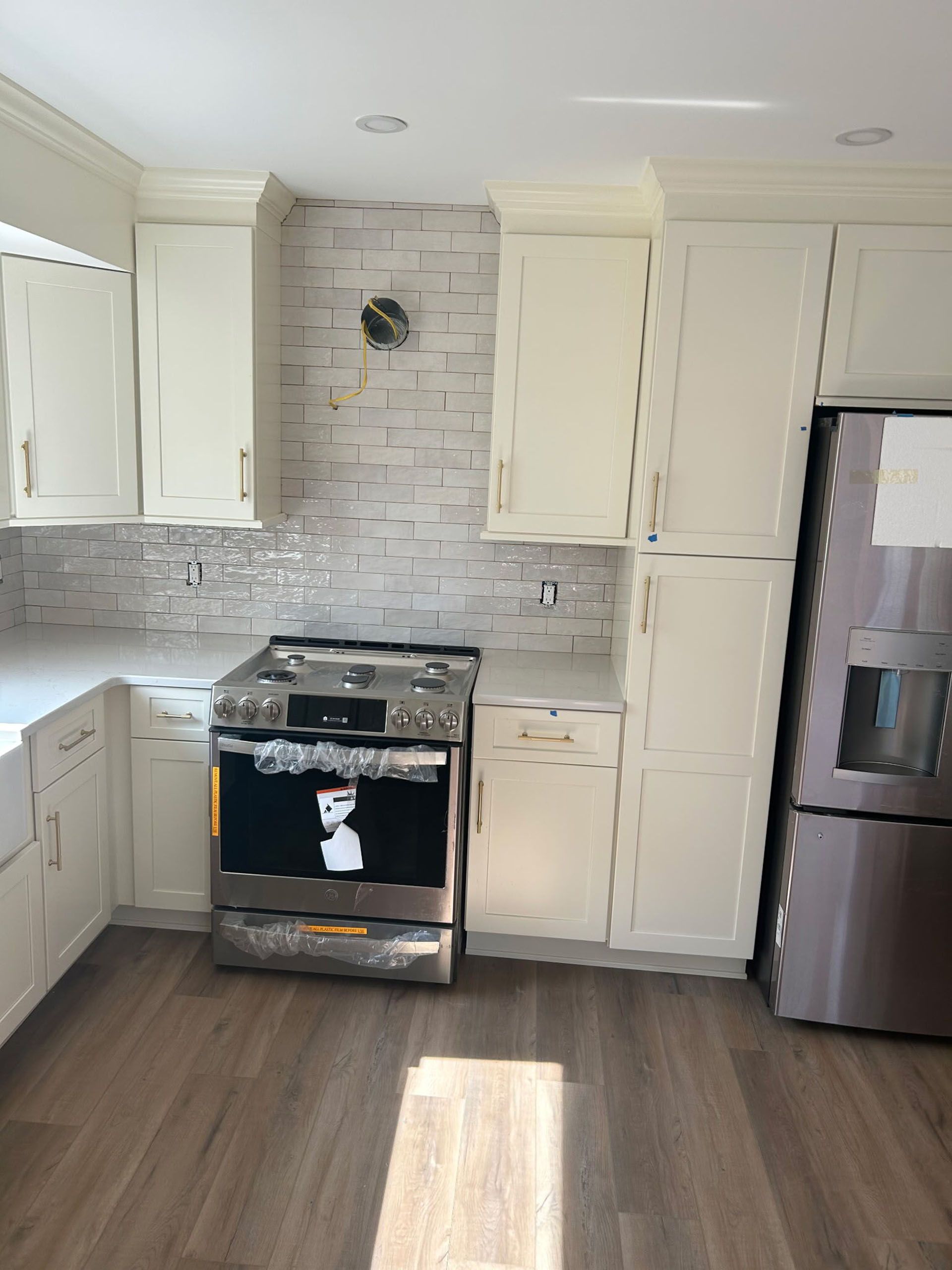 Kitchen with white cabinets, stainless steel appliances, and wood-look flooring.