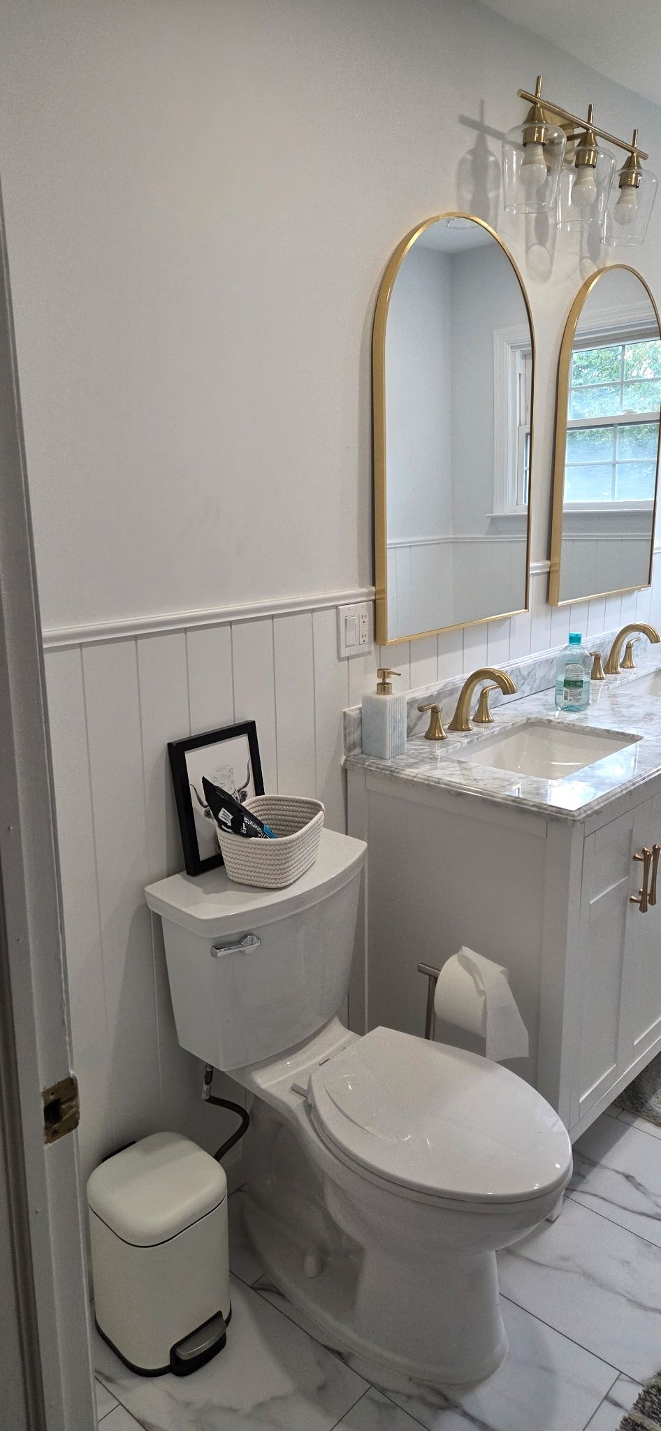 Bathroom with white tile, a white toilet, gold-framed mirrors, and a vanity.