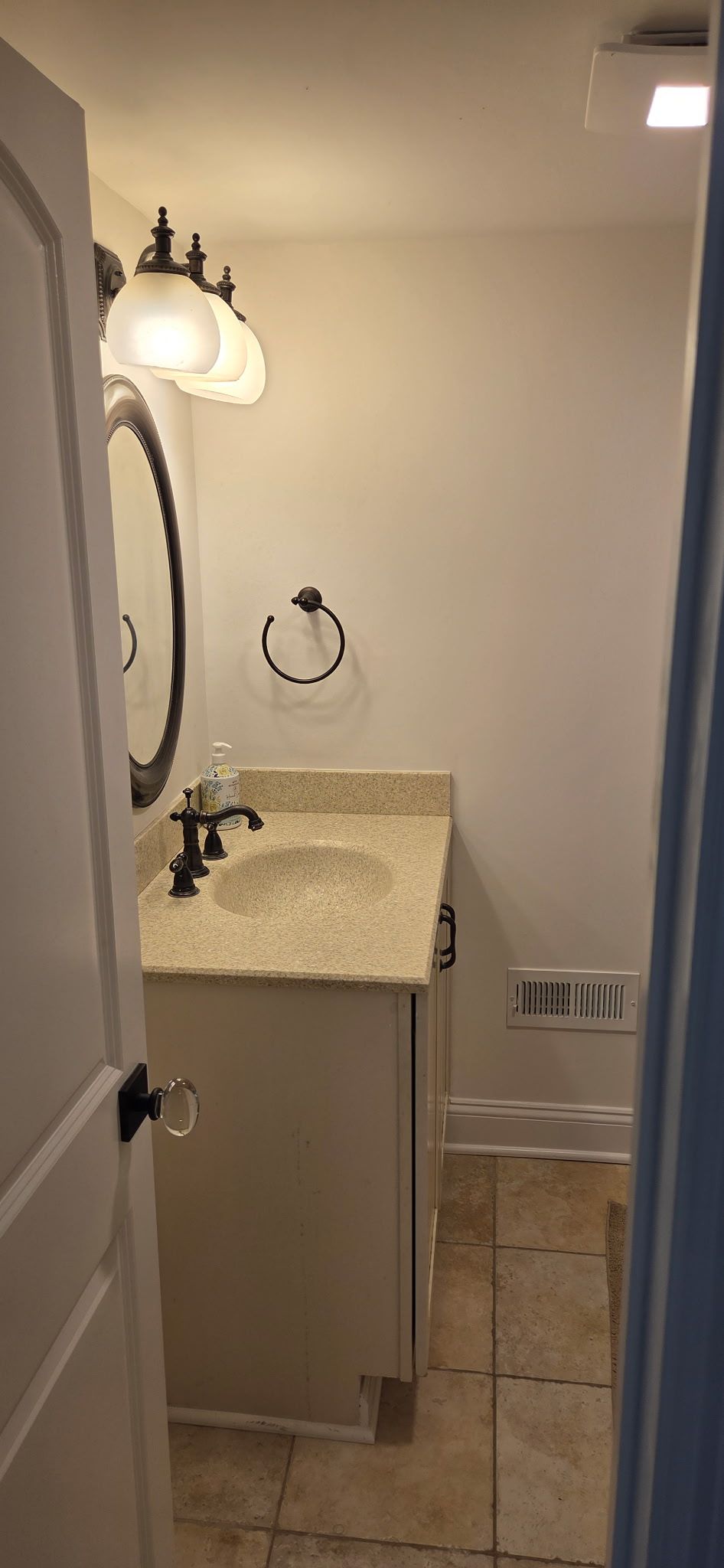 Small bathroom with white walls, vanity, and decorative light fixture.