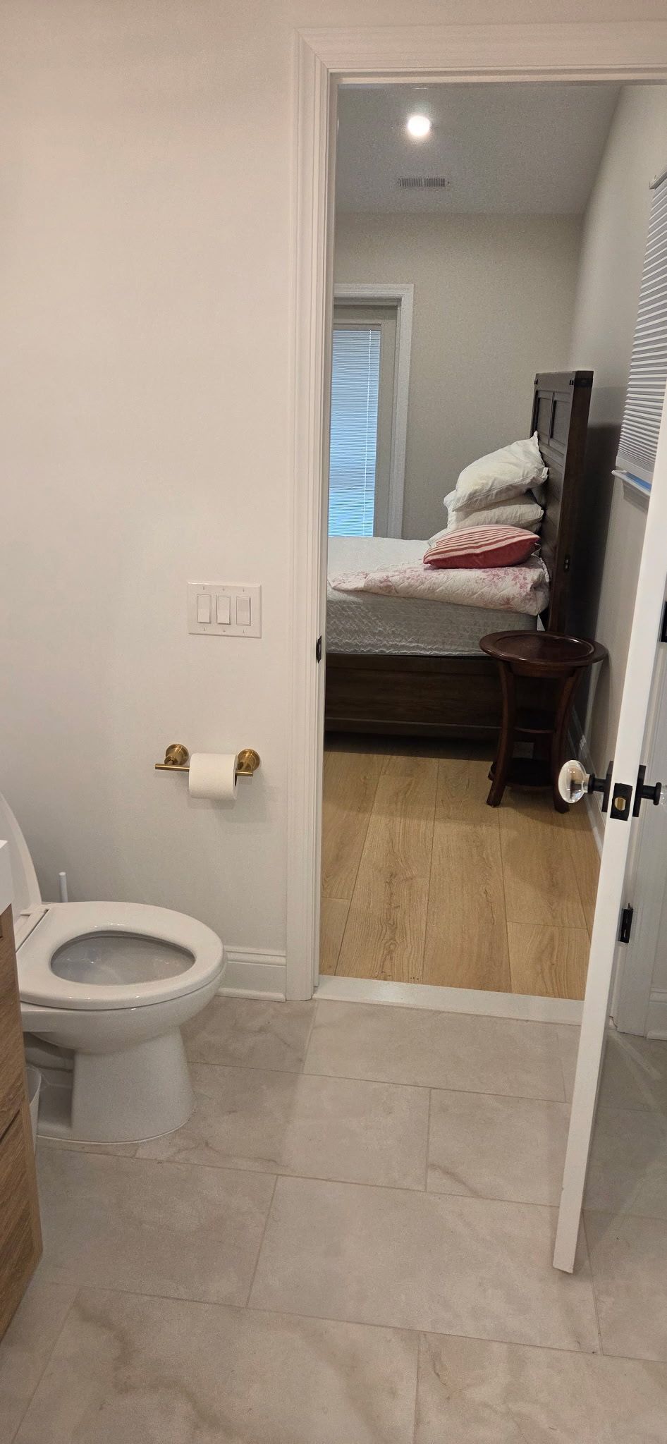 Toilet in bathroom, view of bedroom in the doorway.