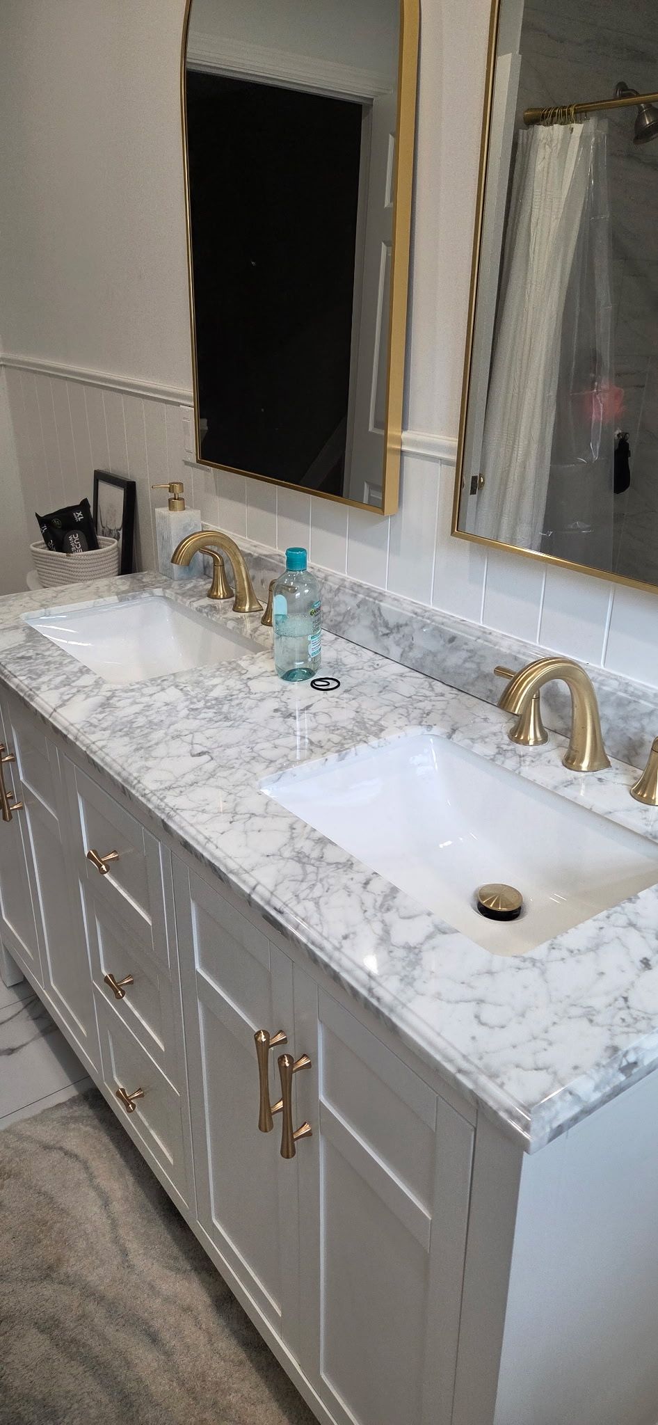White bathroom vanity with gold fixtures and marble countertop.