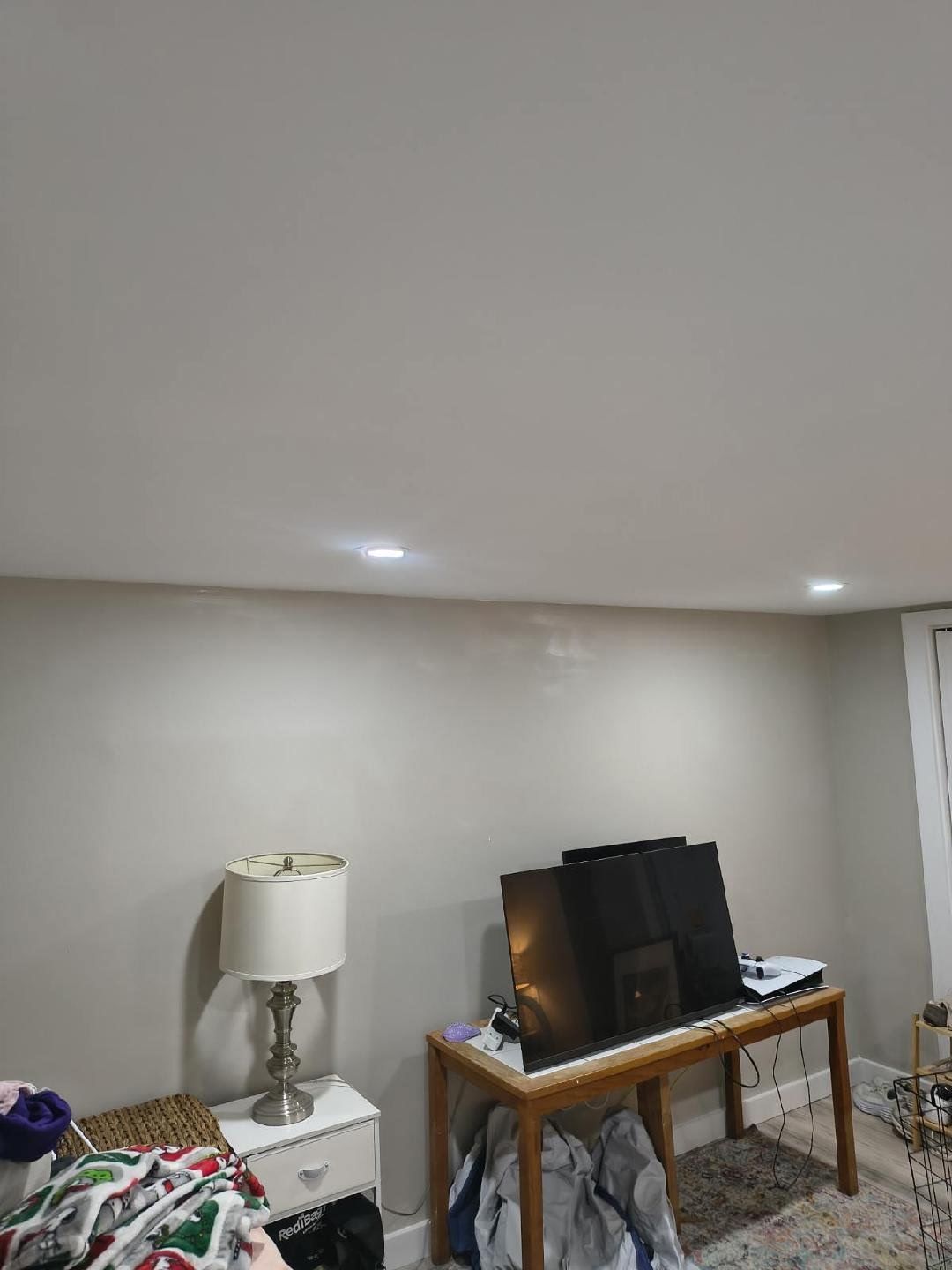 Room with a lamp on a nightstand, and a keyboard on a table.