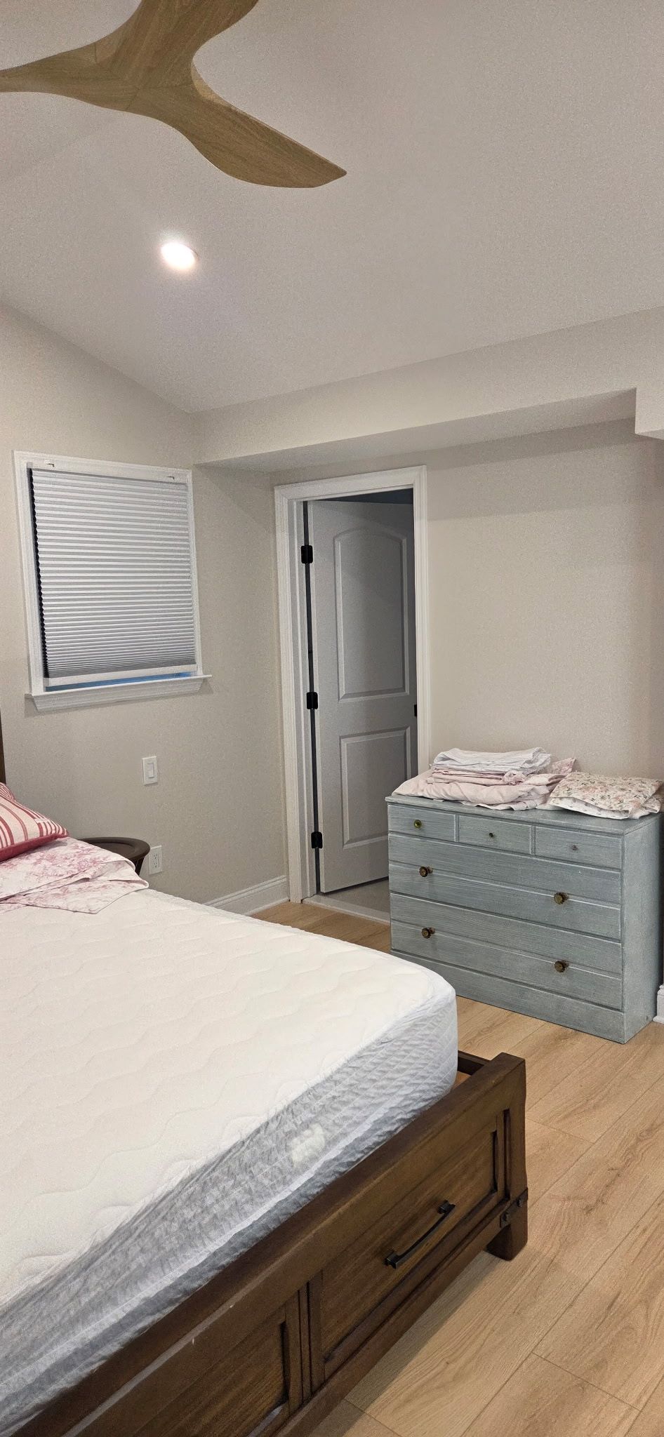Bedroom with wooden bed, blue dresser, and closed white door.