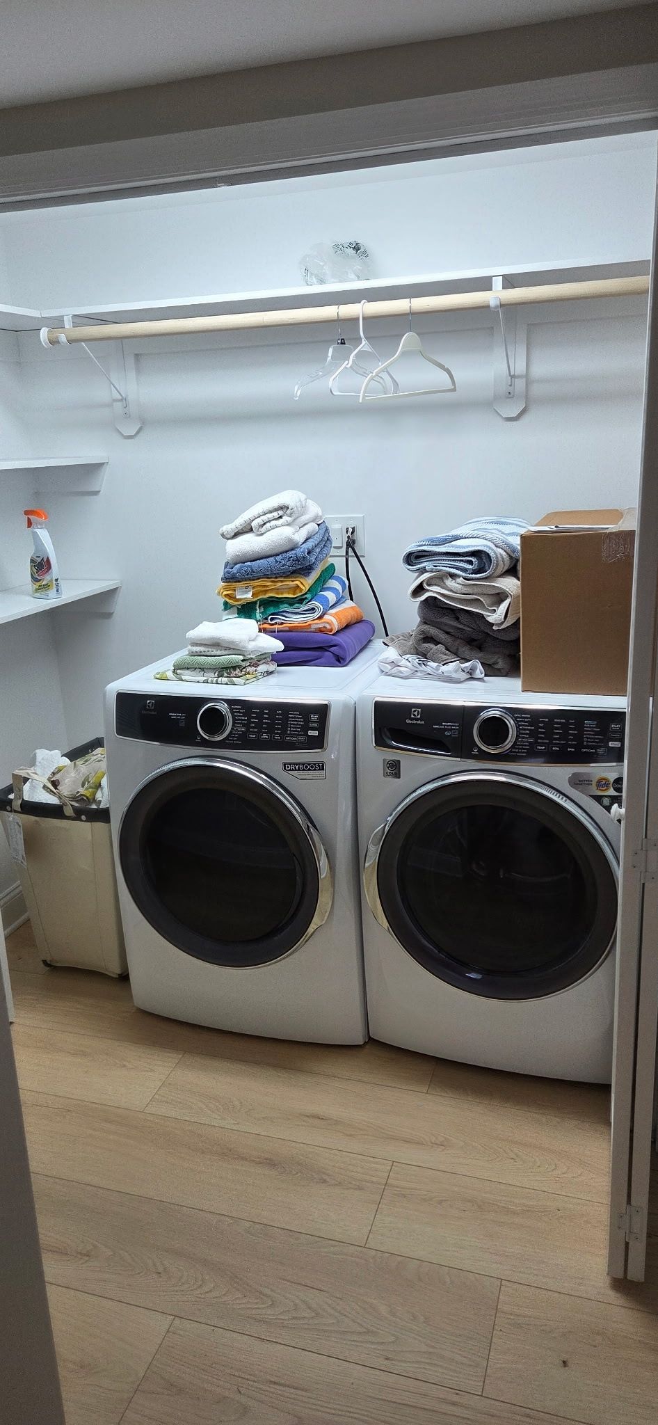 A laundry room with a washer and dryer. Stacks of folded clothes sit on top of the machines.