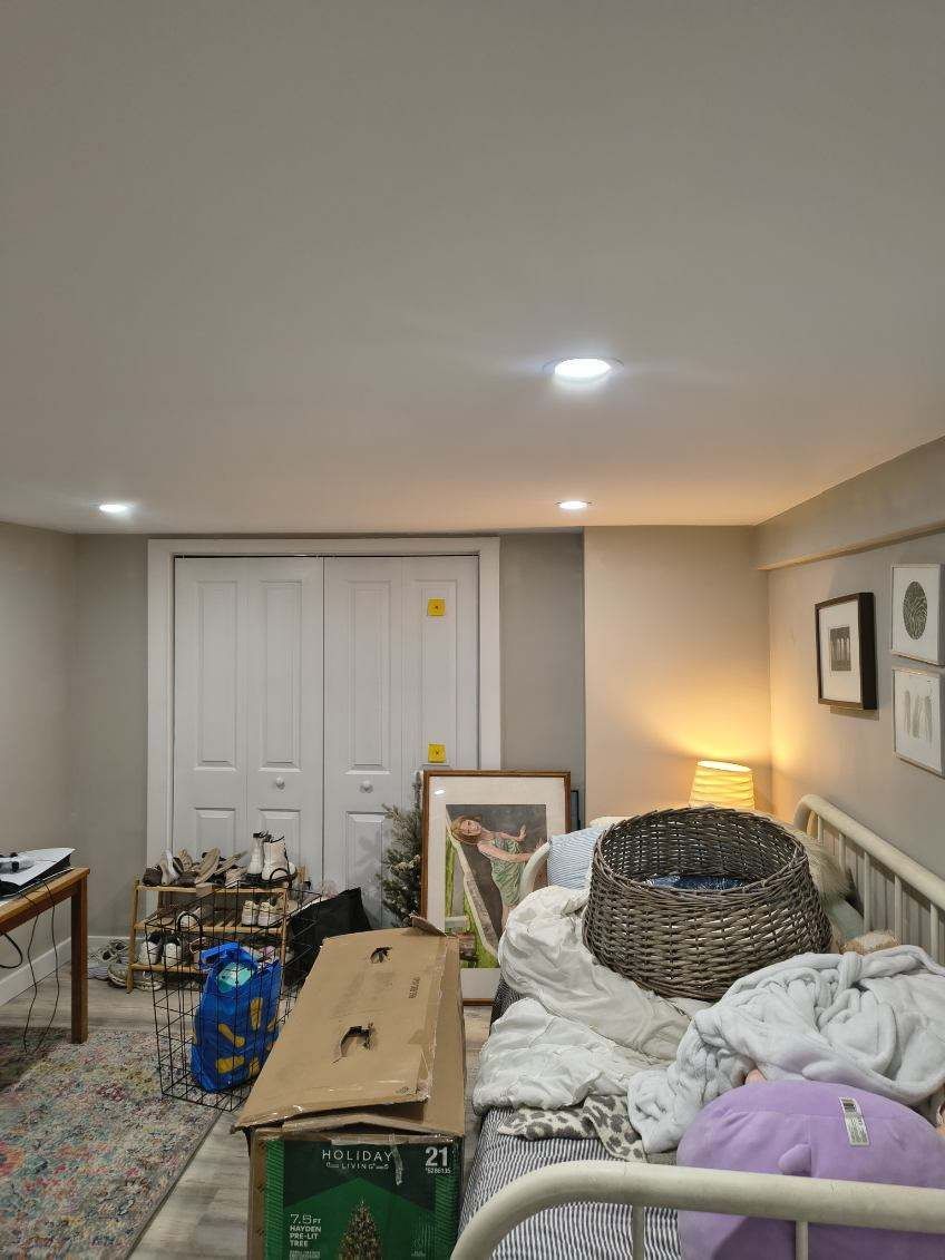 Messy basement room with closed white doors, bed, and scattered items.
