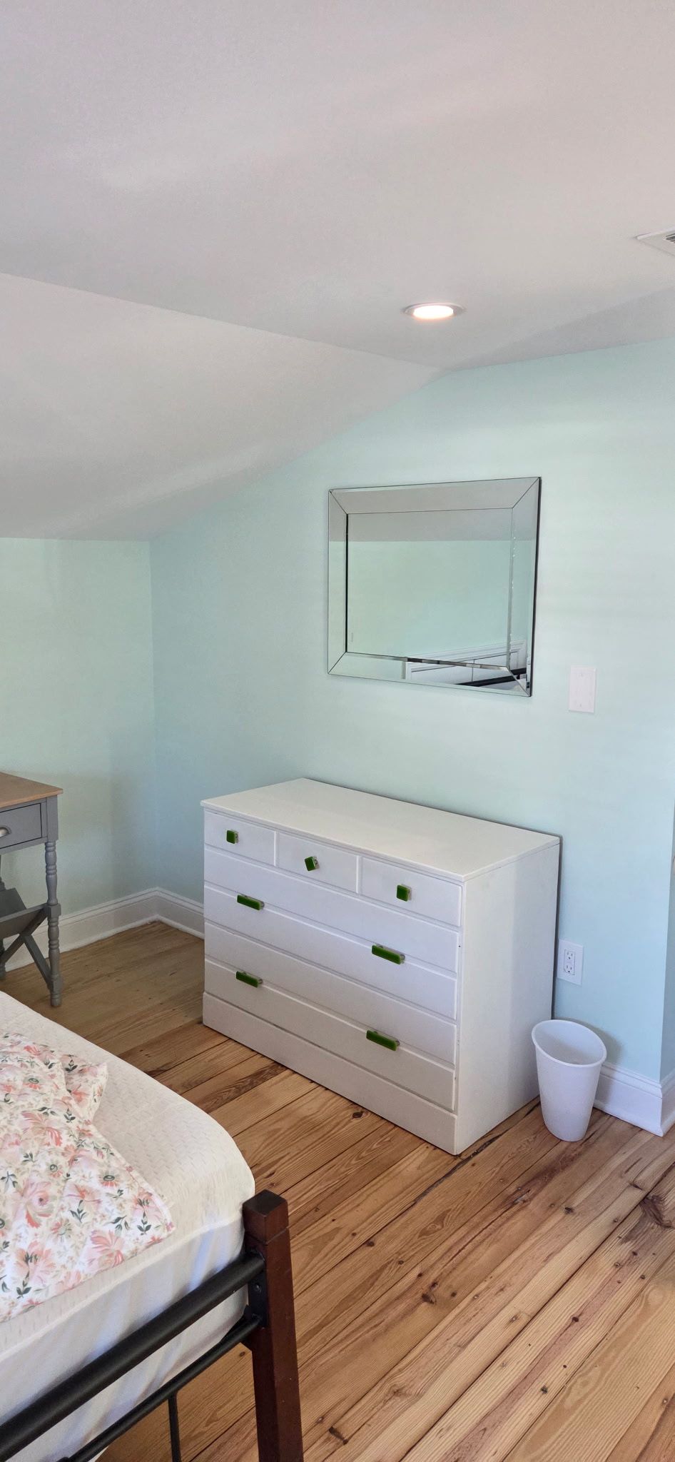 Bedroom with white dresser, mirror, wood floor, and light blue walls.