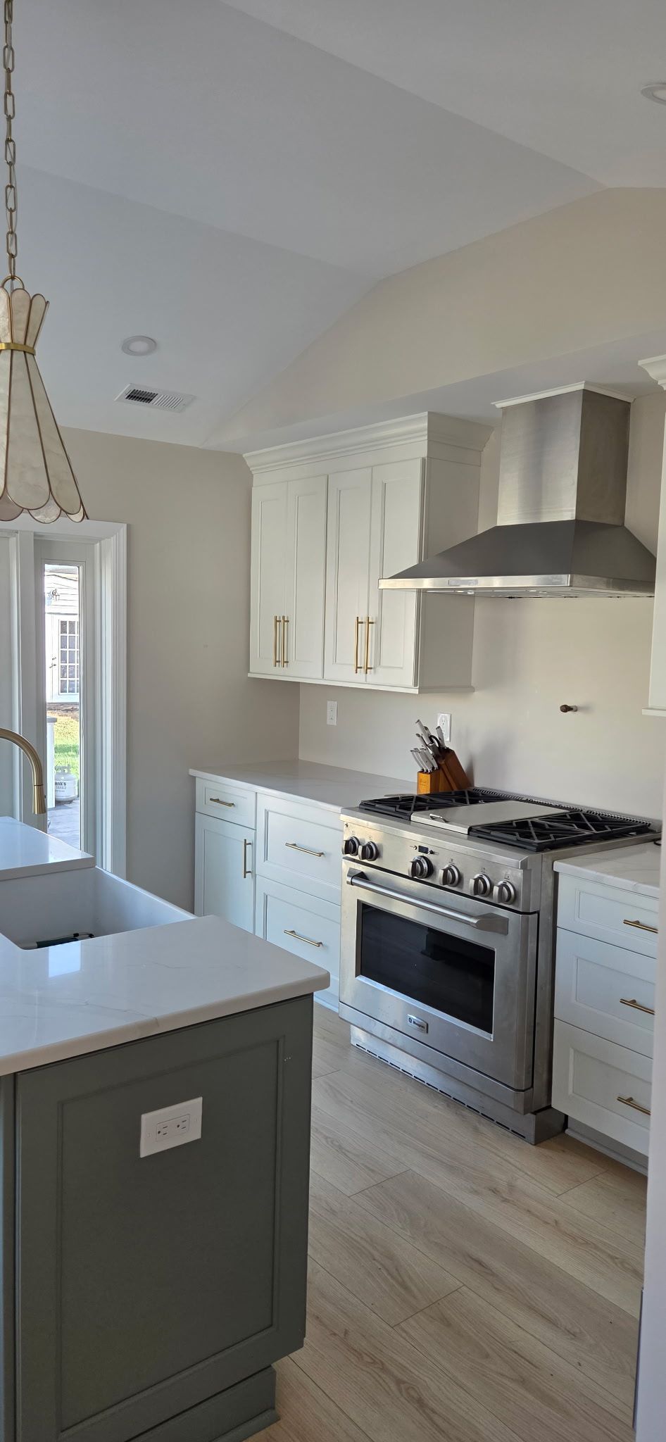 Kitchen with light cabinets, stainless steel appliances, and gray island.