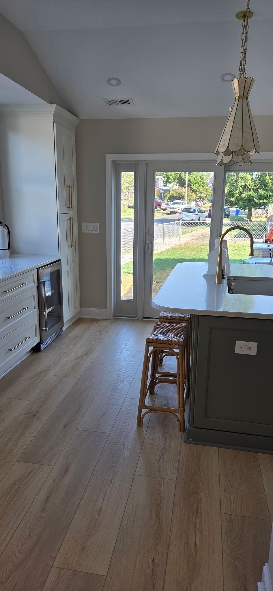 Kitchen interior with light wood floors, white cabinets, and island with a wooden stool.