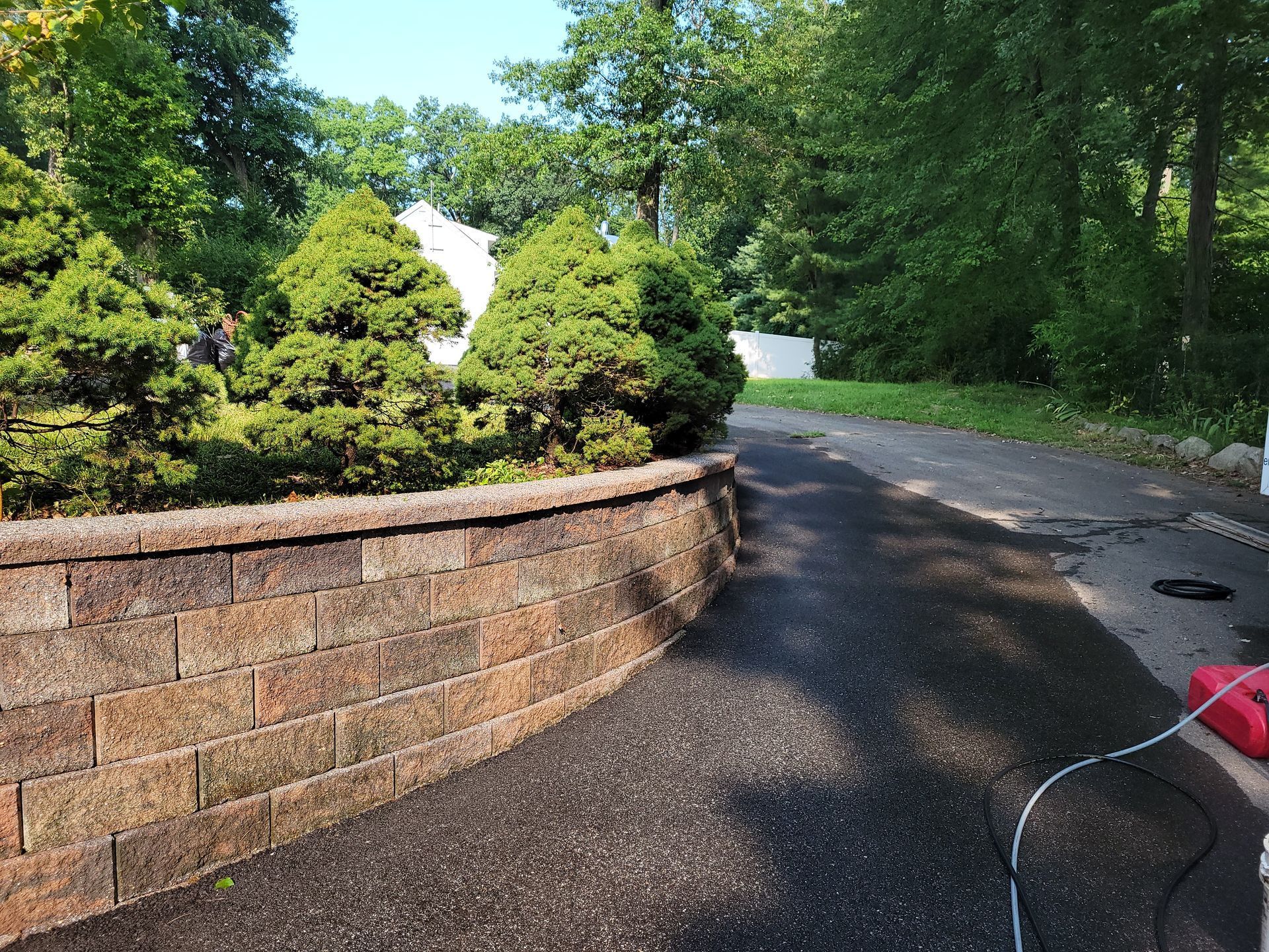 A brick wall along the side of a road with trees in the background