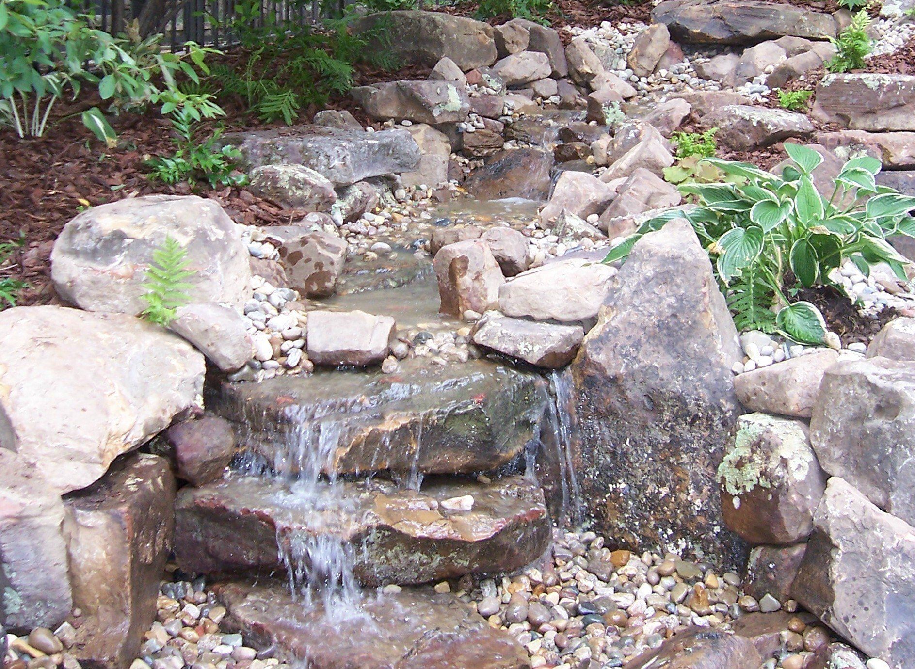 Natural stone wall water feature with gravel accents