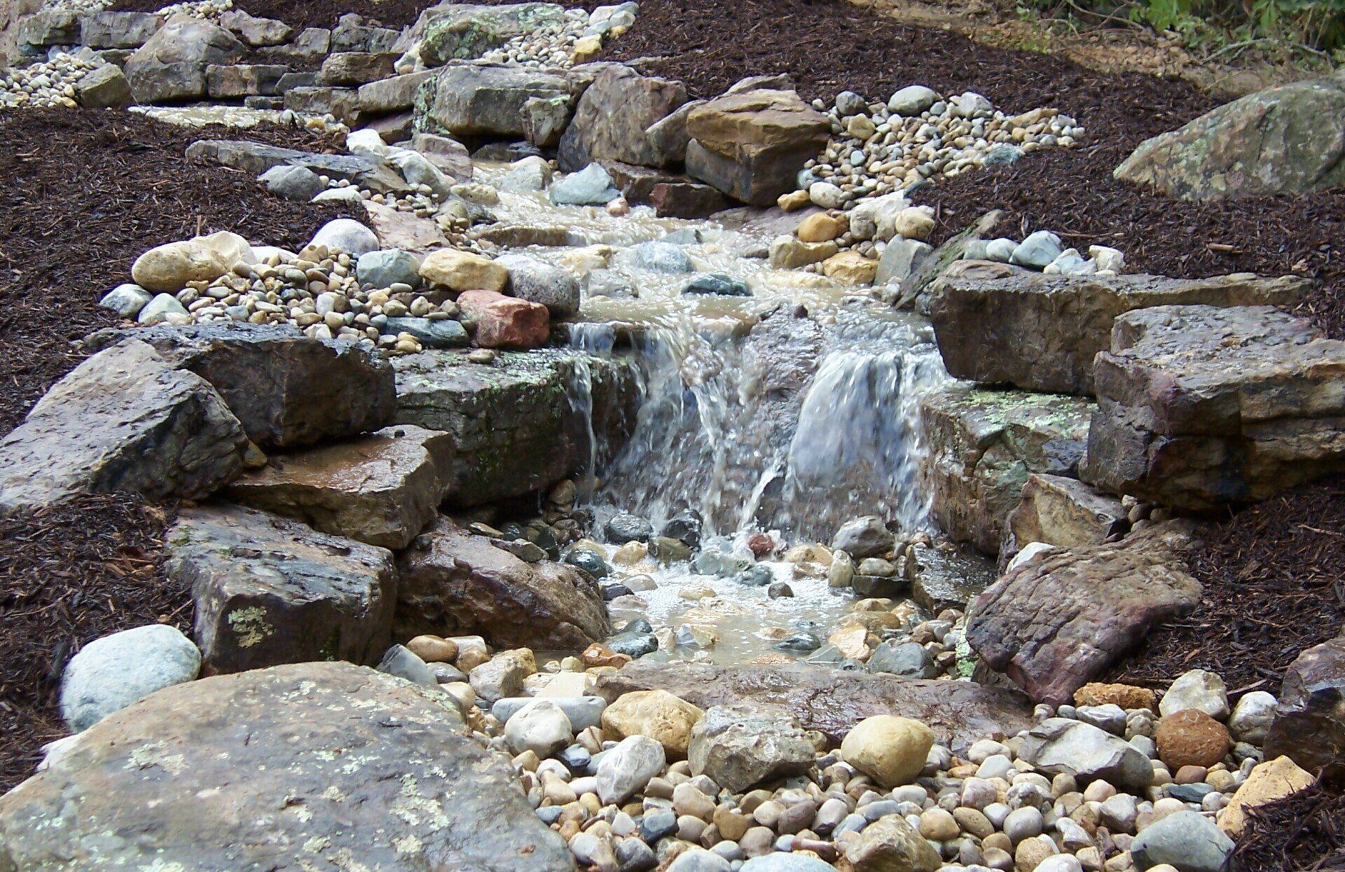 Natural stone wall water feature with gravel accents