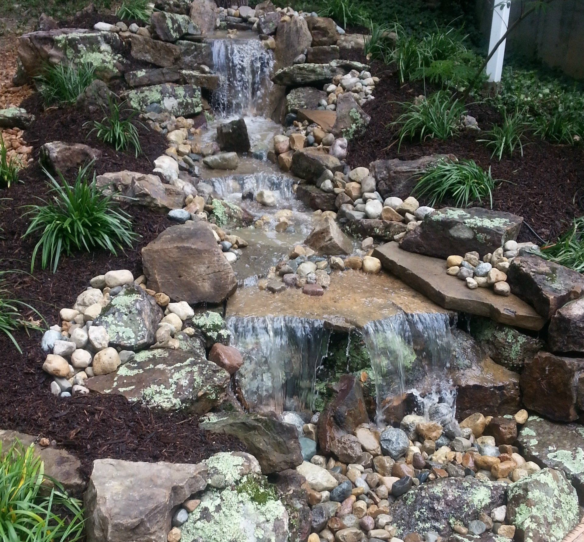 Natural stone wall water feature with gravel accents