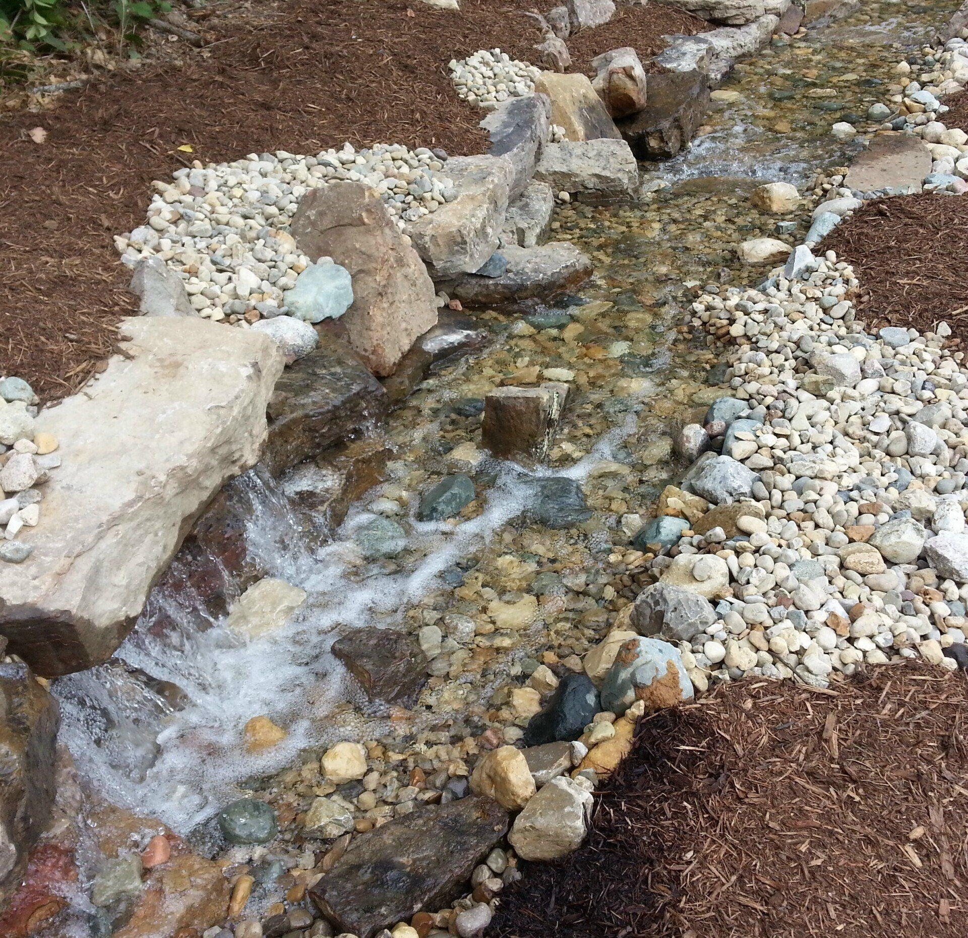 Natural stone wall water feature with gravel accents