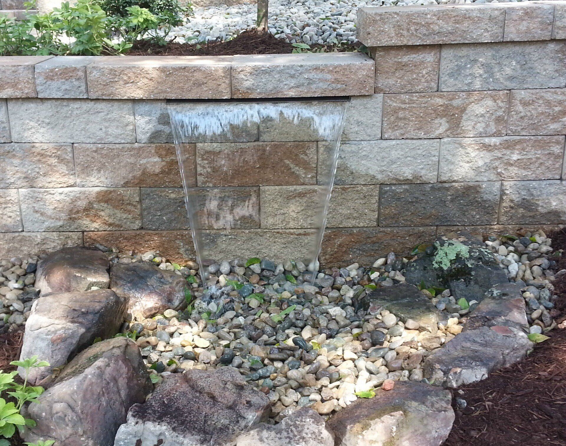 Natural stone wall water feature with gravel accents