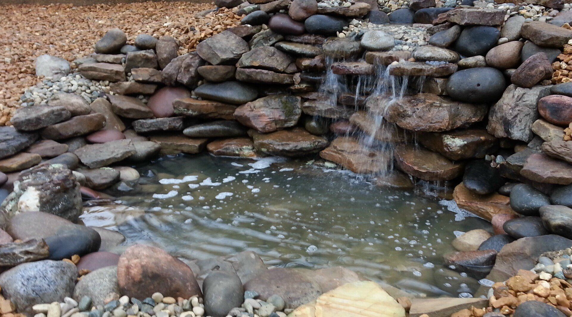 Natural stone wall water feature with gravel accents