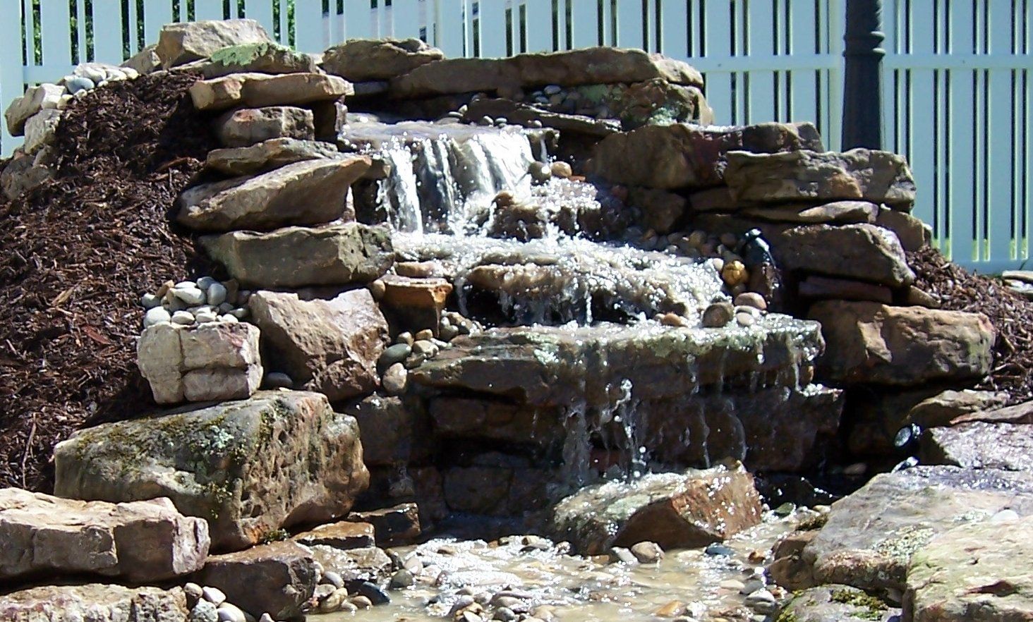 Natural stone wall water feature with gravel accents