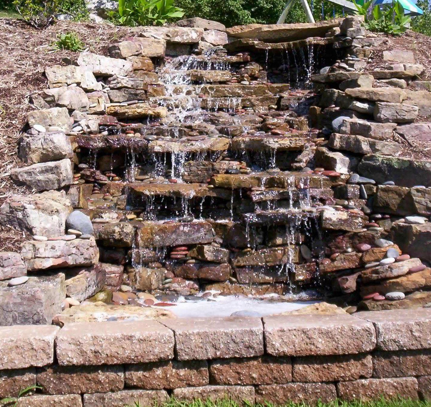 Natural stone wall water feature with gravel accents
