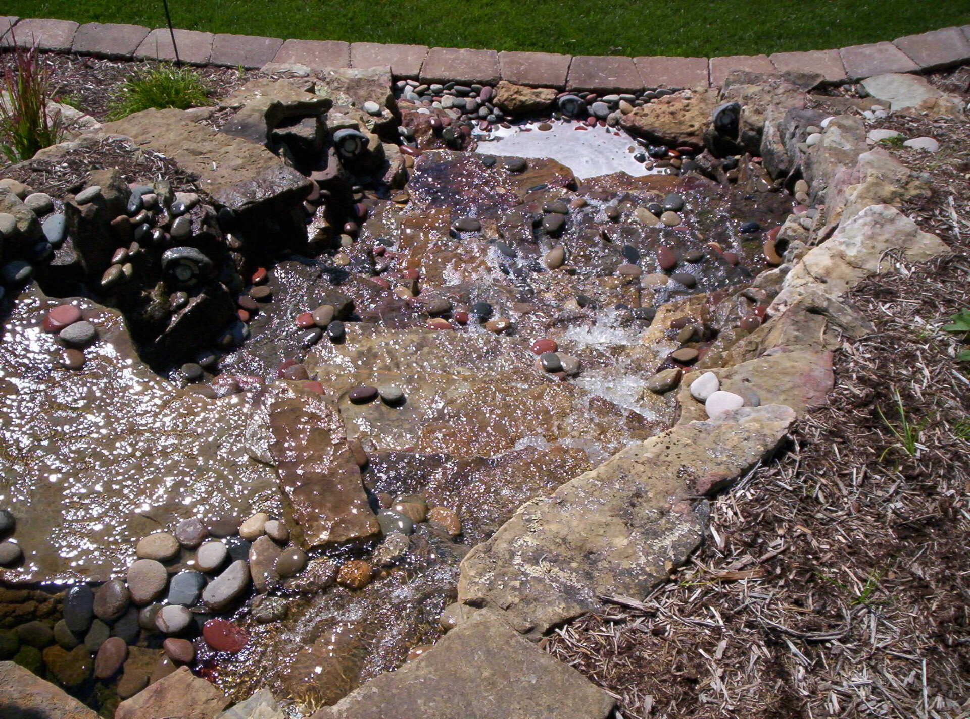 Natural stone wall water feature with gravel accents