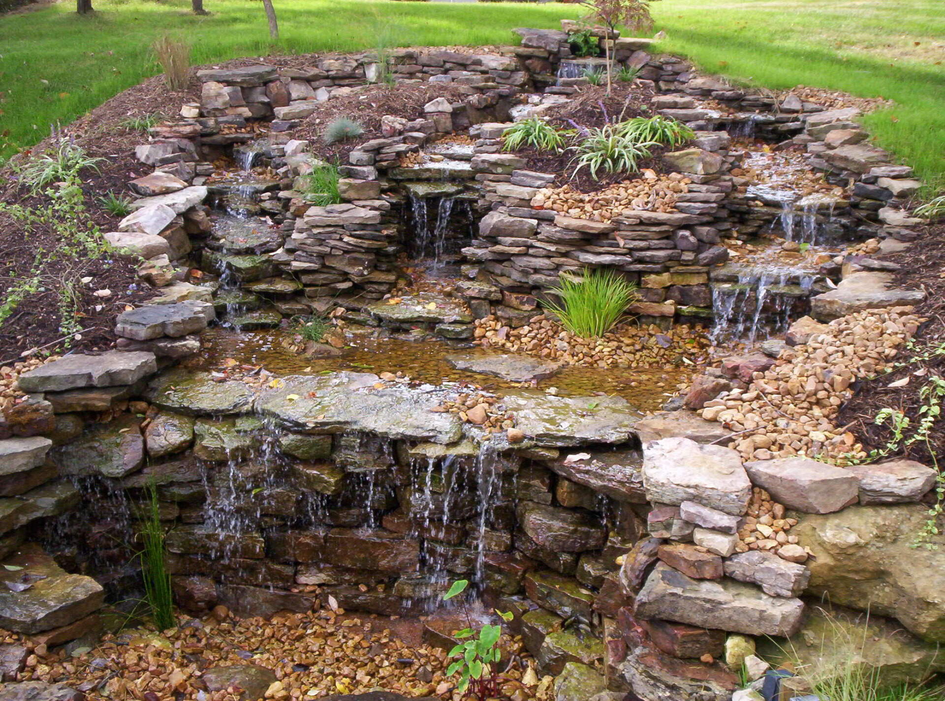 Natural stone wall water feature with gravel accents