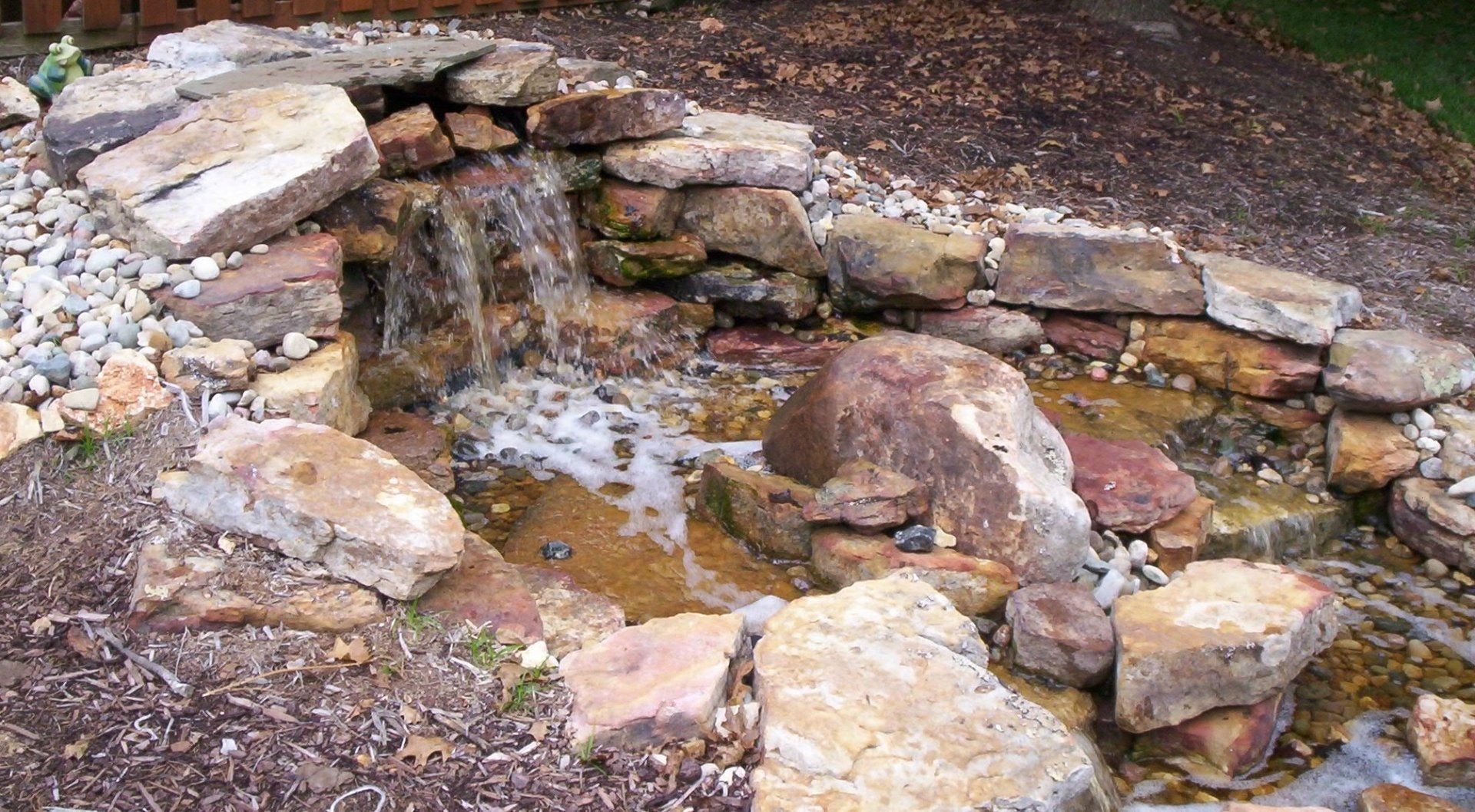 Natural stone wall water feature with gravel accents