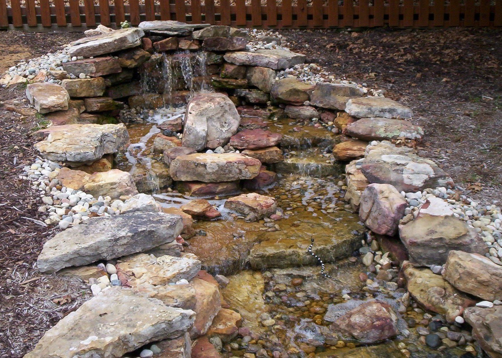 Natural stone wall water feature with gravel accents
