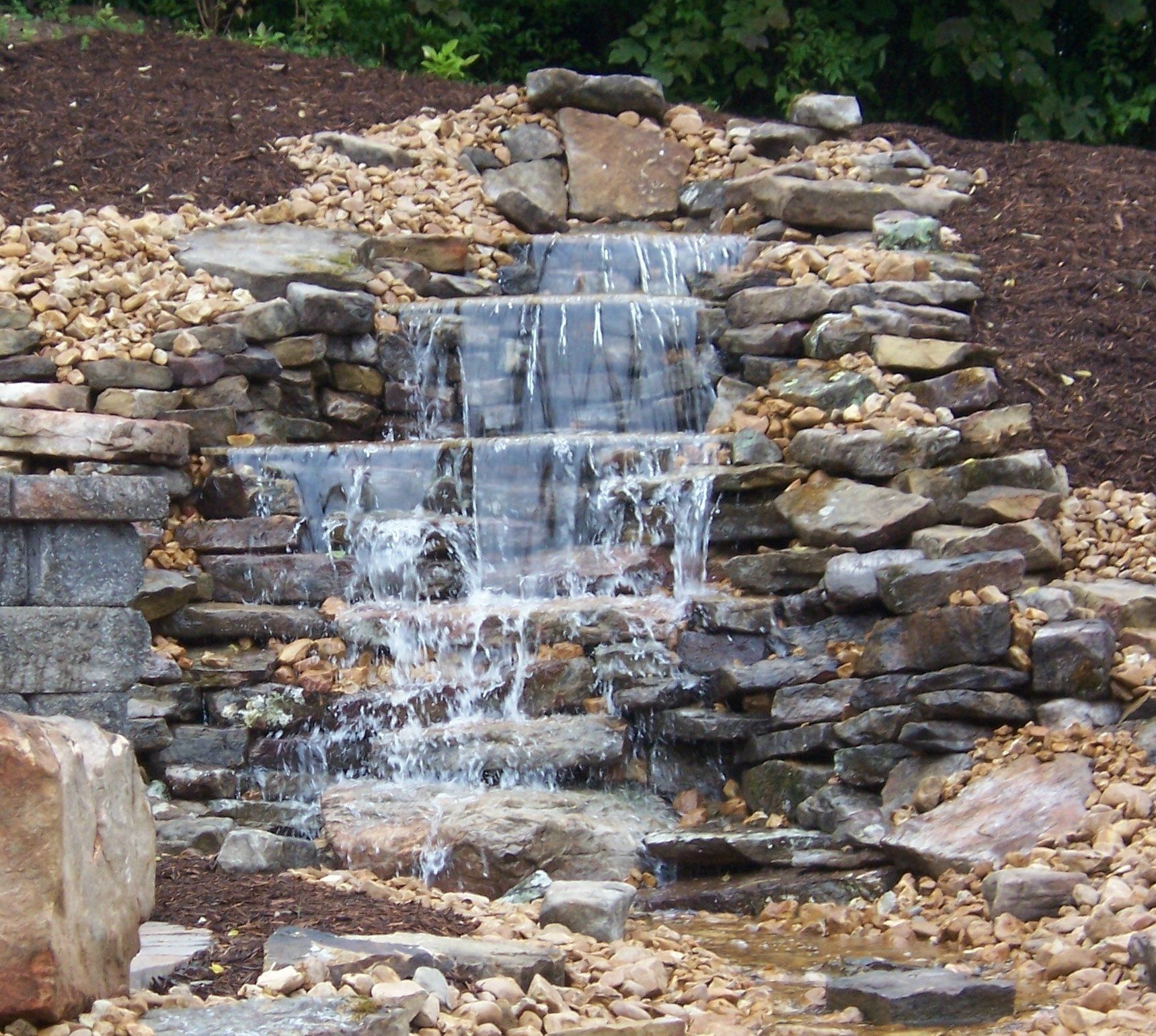Natural stone wall water feature with gravel accents