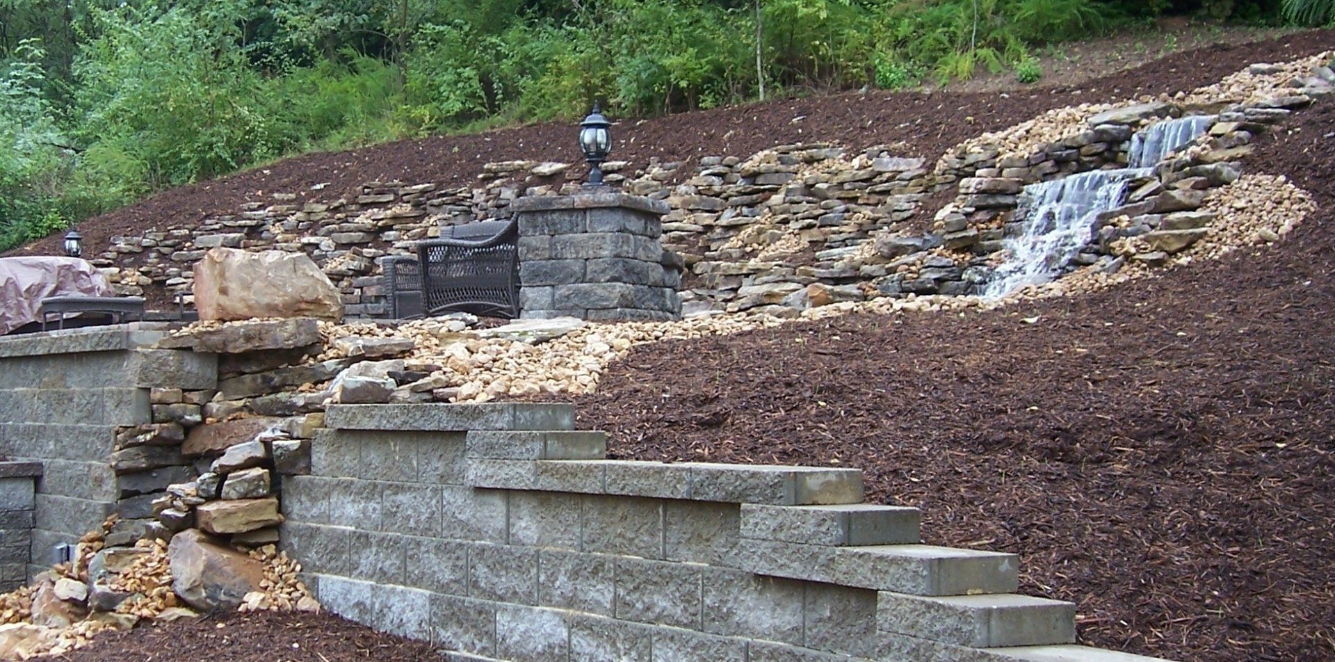 Natural stone wall water feature with gravel accents