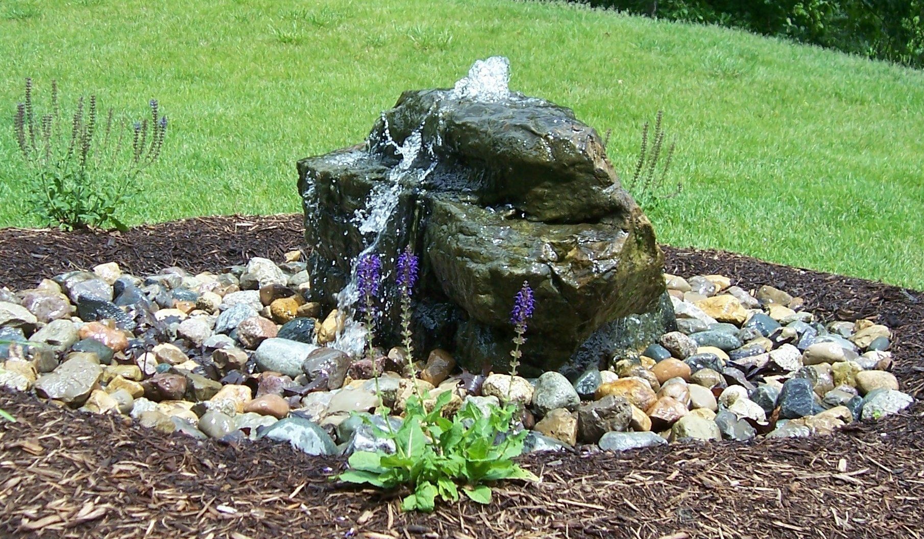 Natural stone wall water feature with gravel accents