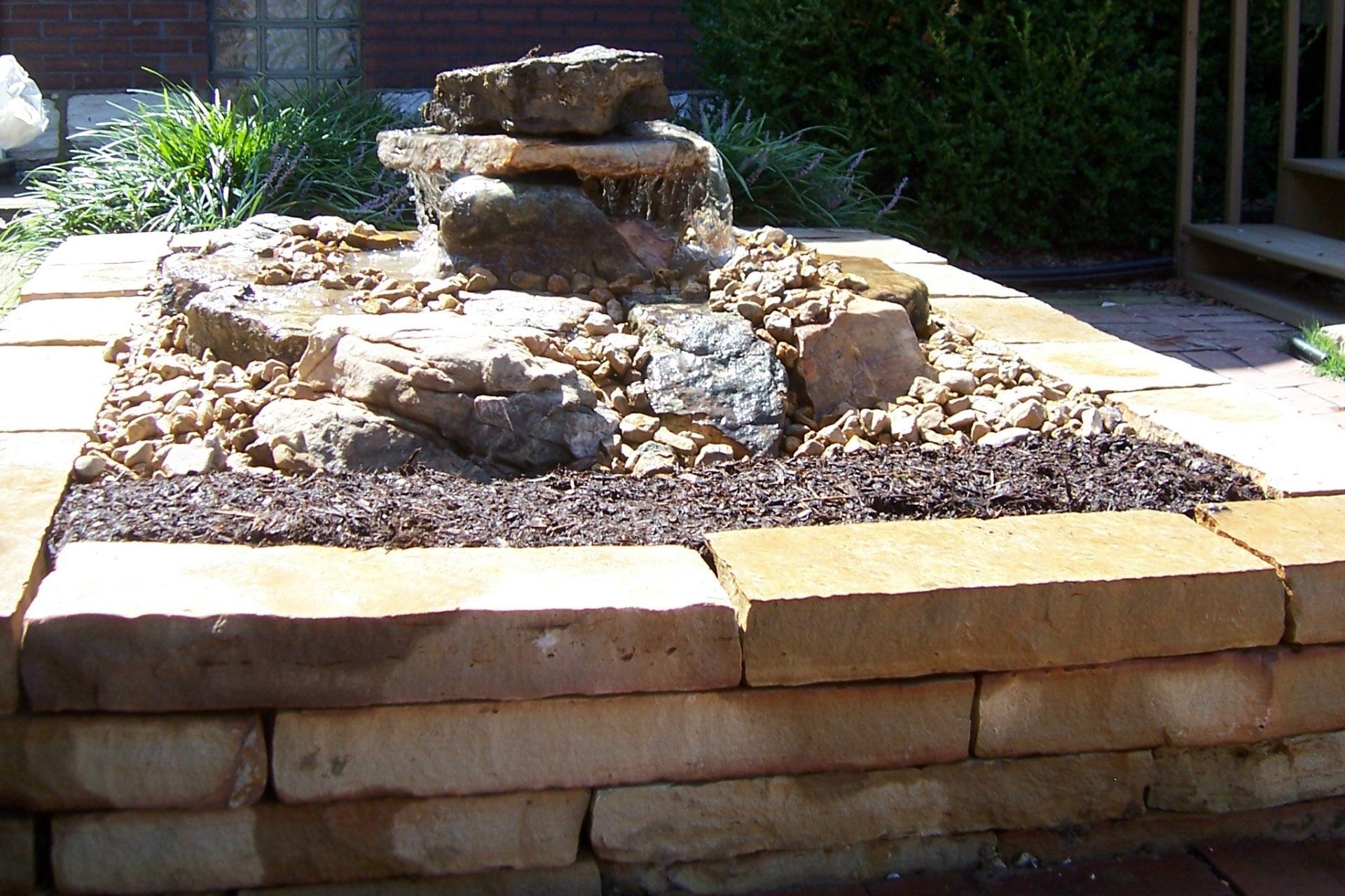 Natural stone wall water feature with gravel accents