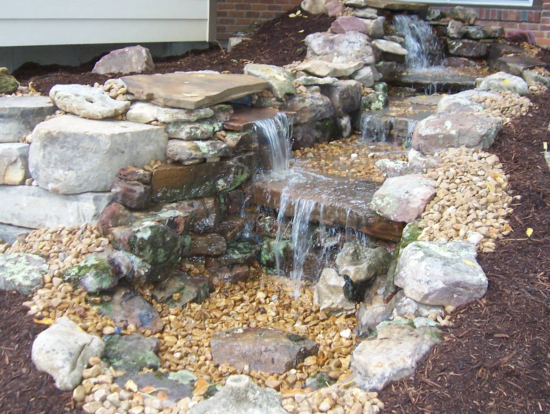 Natural stone wall water feature with gravel accents