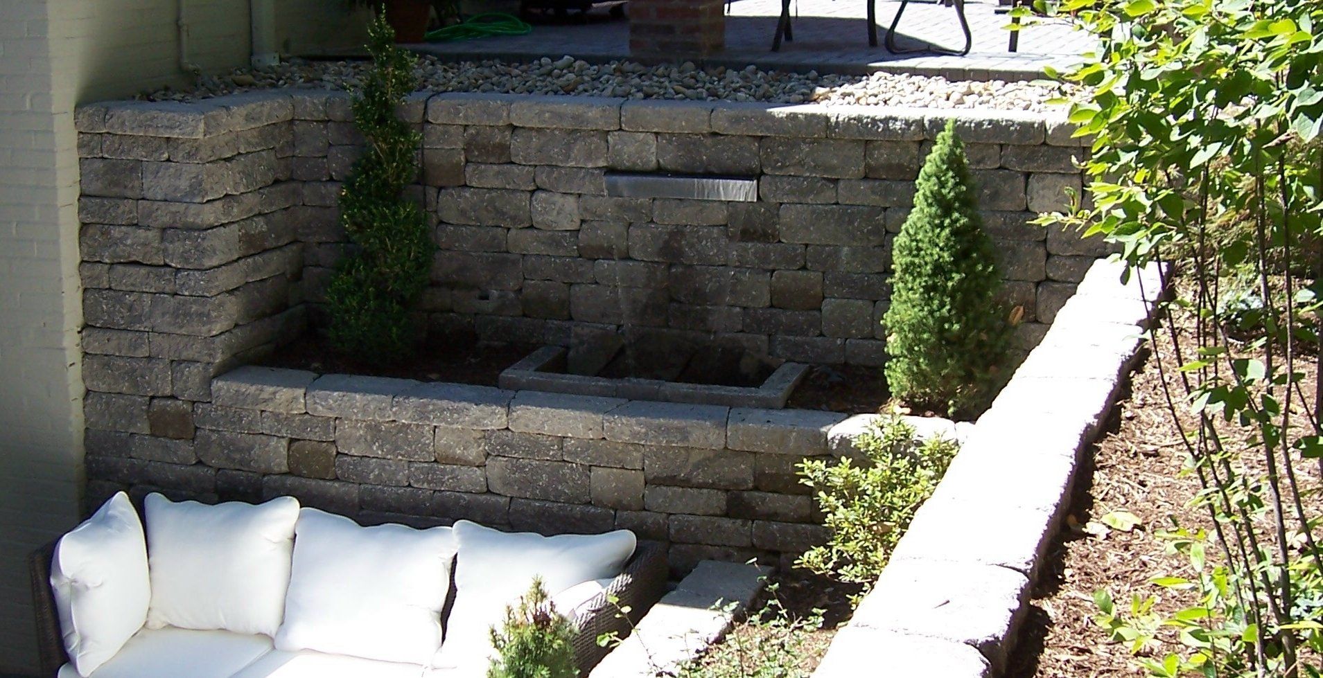 Natural stone wall water feature with gravel accents