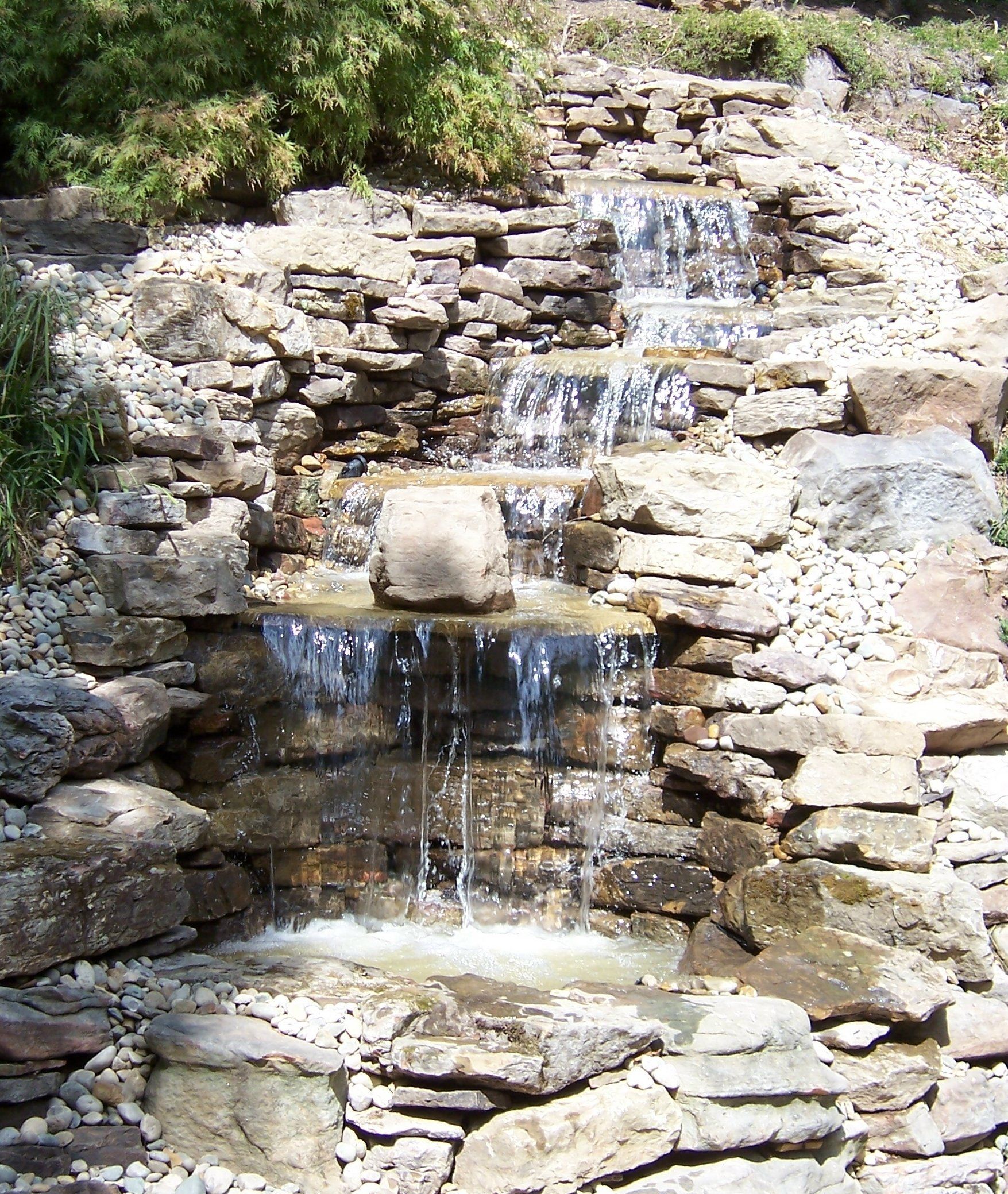 Natural stone wall water feature with gravel accents
