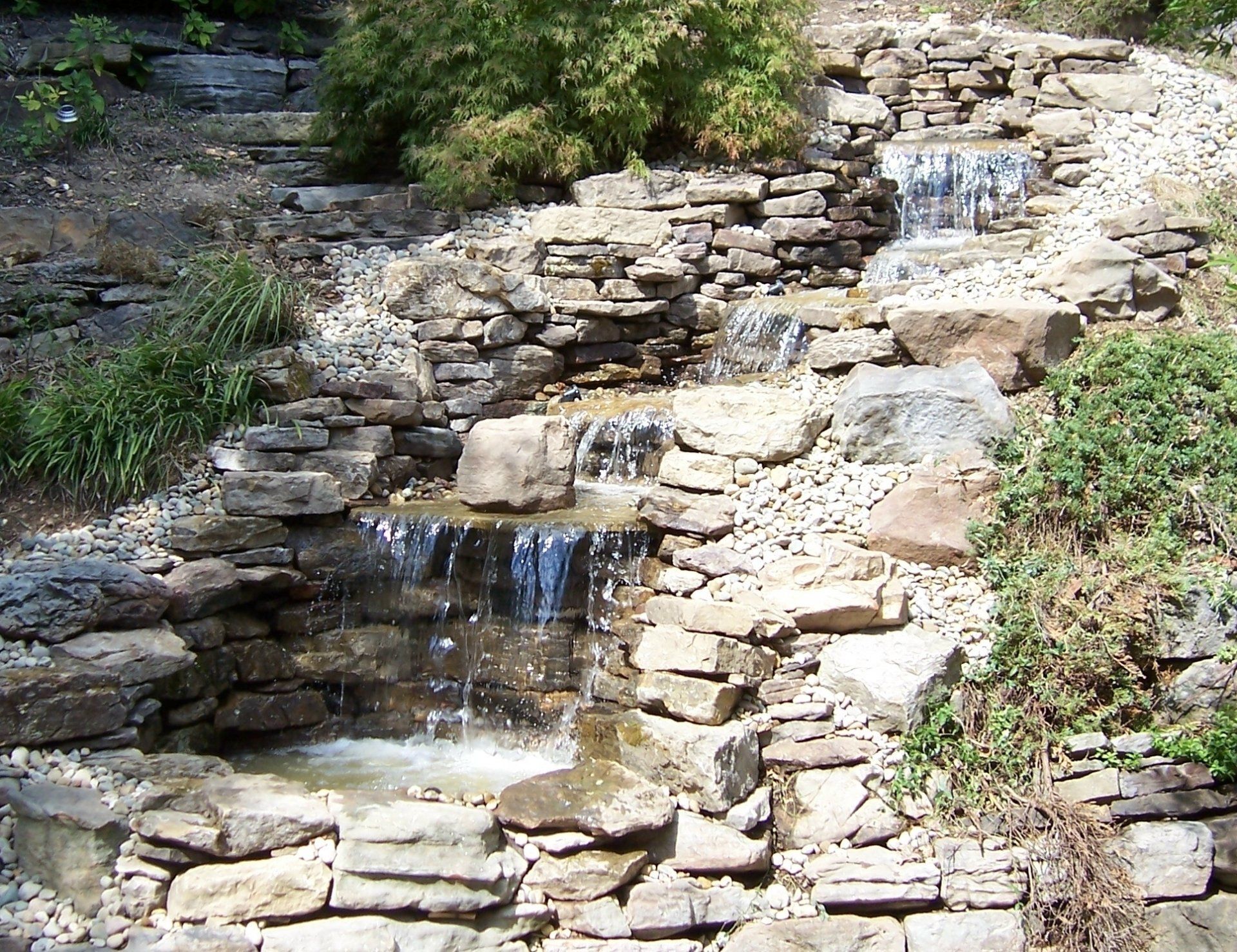 Natural stone wall water feature with gravel accents