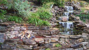 Natural Weathered stone water feature with gas fire-pit, gravel accents & landscaping