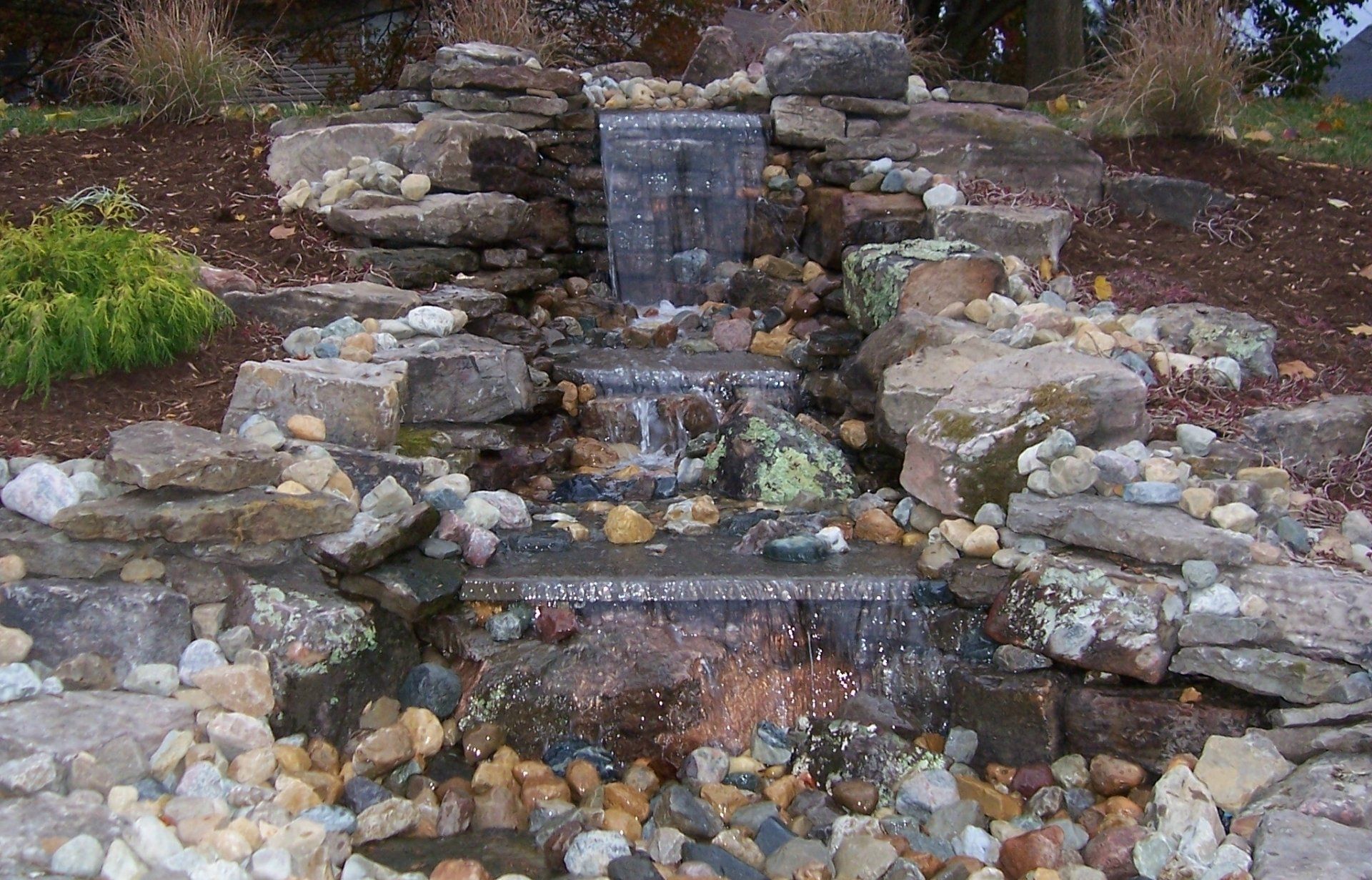 Natural stone wall water feature with gravel accents
