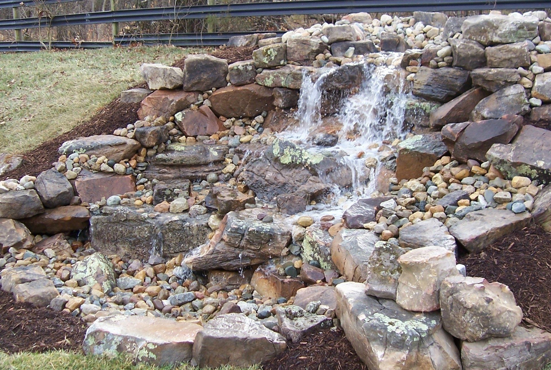 Natural stone wall water feature with gravel accents