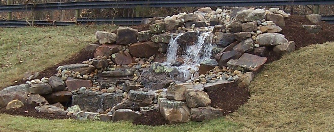 Natural stone wall water feature with gravel accents