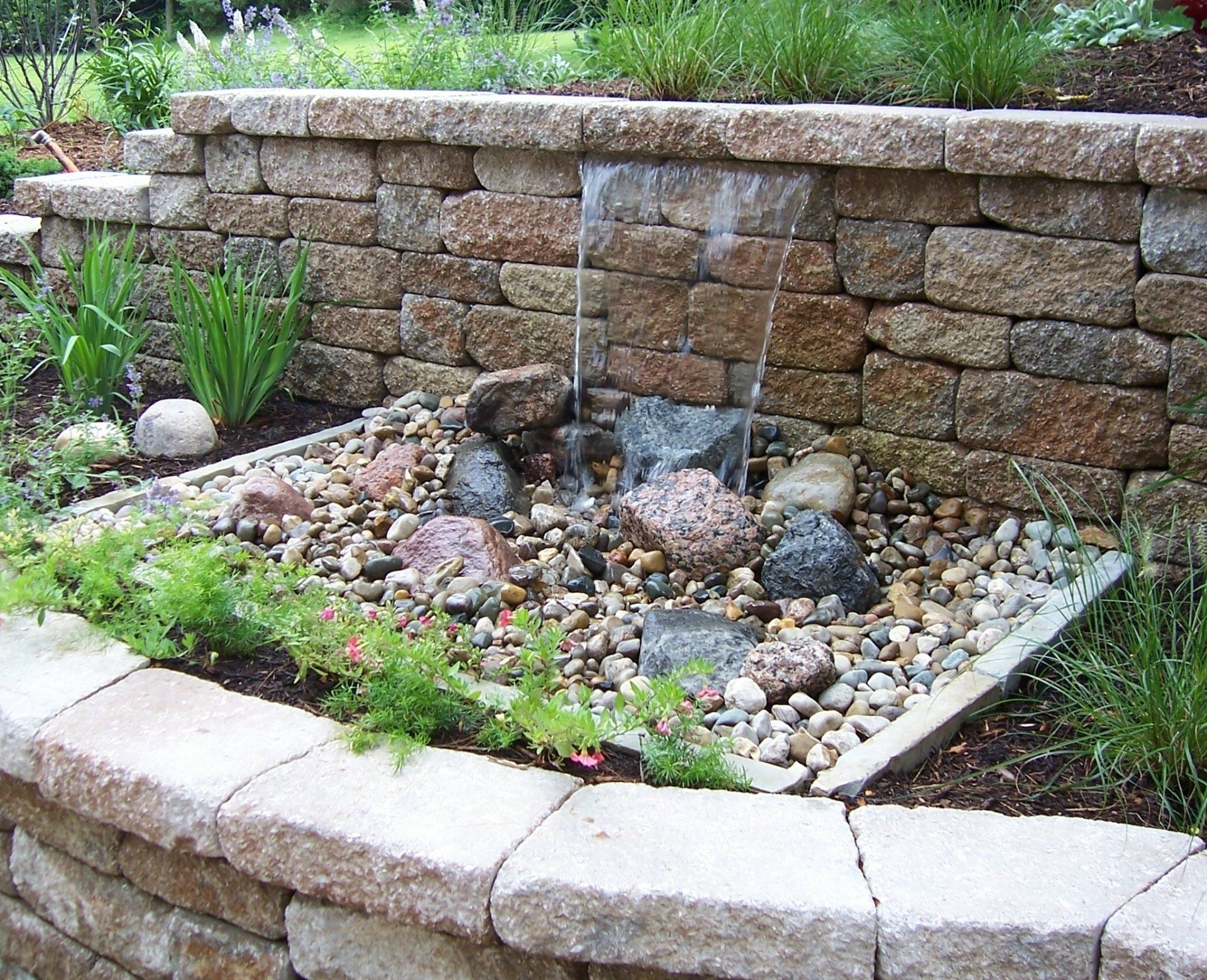Natural stone wall water feature with gravel accents