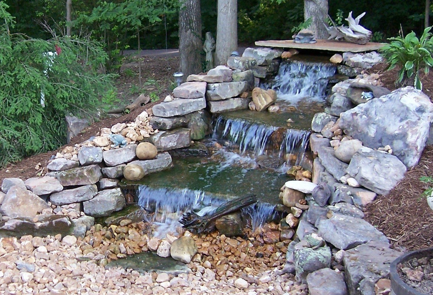 Natural stone wall water feature with gravel accents