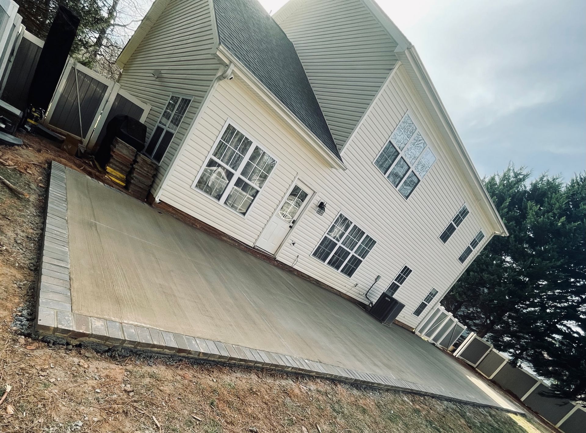 Beige house with concrete patio, gray border, and brown grass.