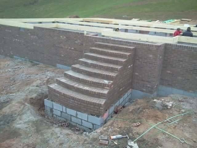 Brick staircase under construction, built into a brick retaining wall.