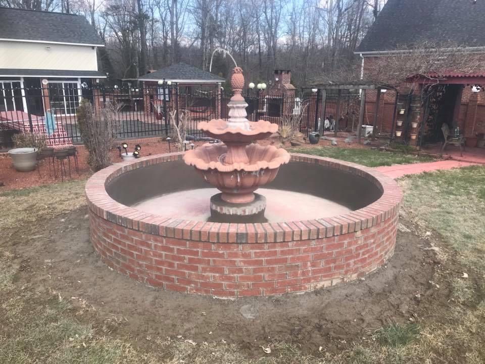 Brick fountain in a circular brick basin, backyard setting.