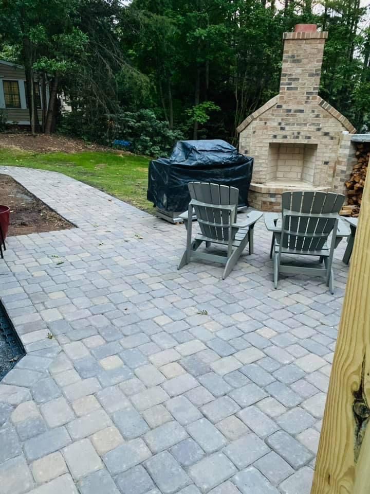 Brick patio with Adirondack chairs, grill, and brick fireplace.