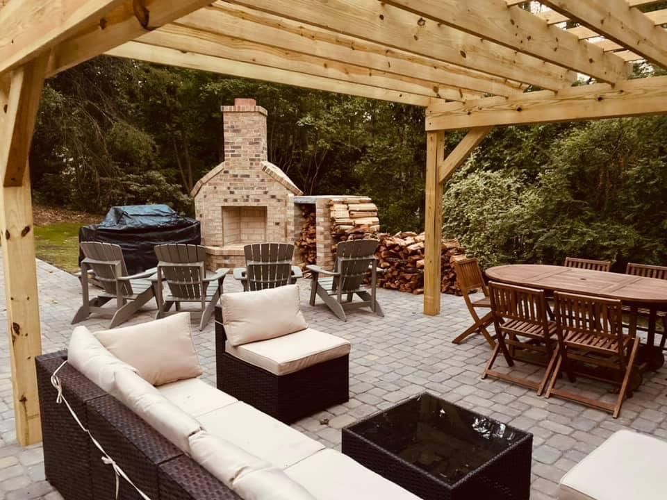 Patio with pergola, outdoor seating, brick fireplace, and wood storage.