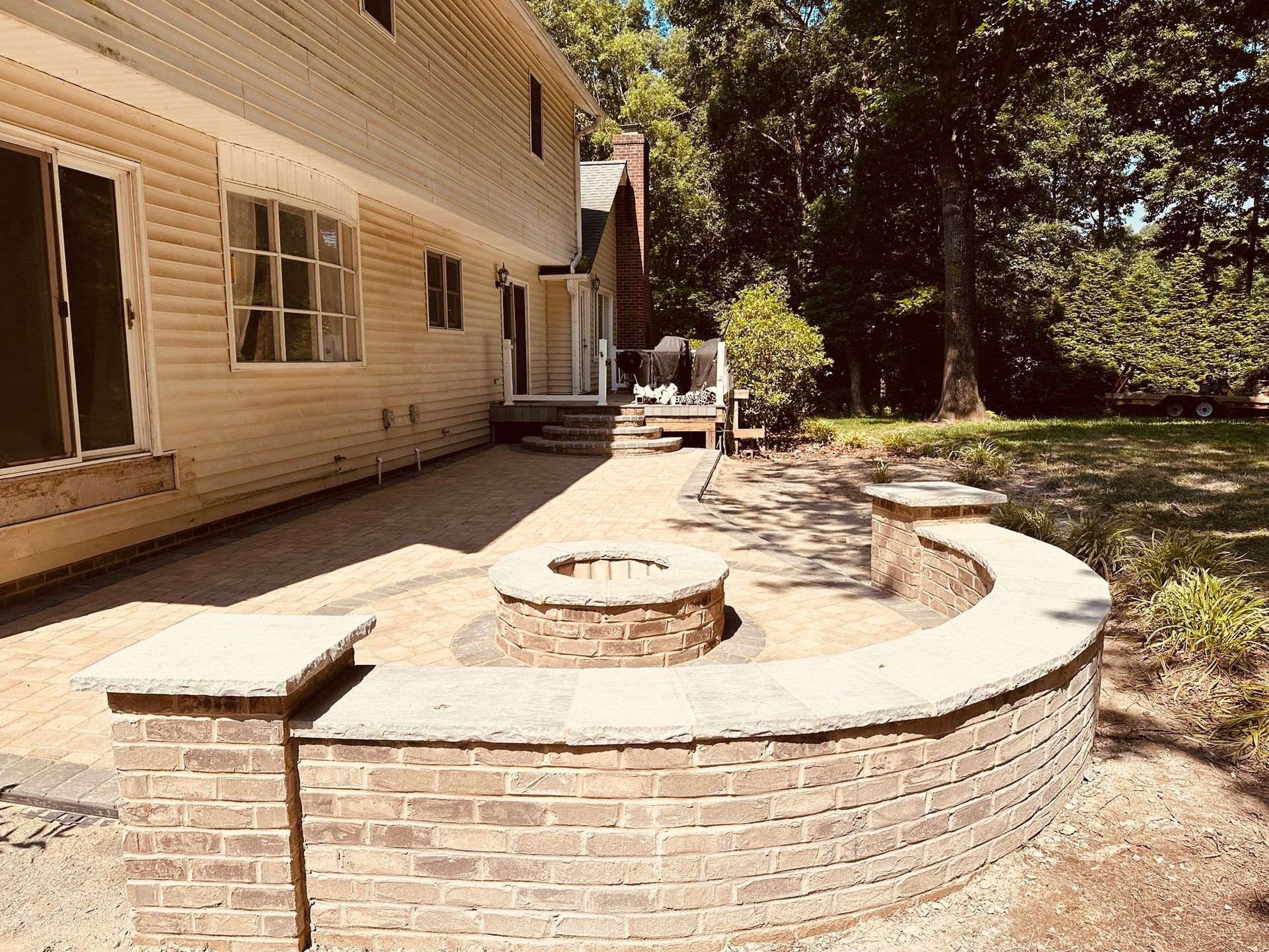 Backyard patio with brick retaining walls, fire pit, and beige siding.