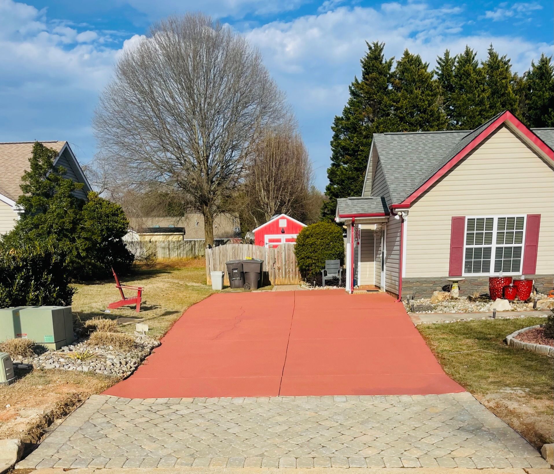 Red brick driveway in front of a house. A small red shed is visible in the distance.