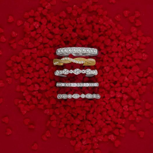 Five sparkling rings arranged vertically on a red rose petal background