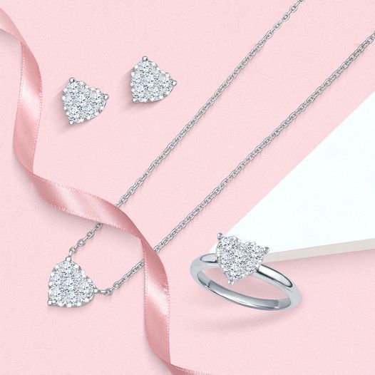 Silver heart-shaped jewelry set on pink background with ribbon accents